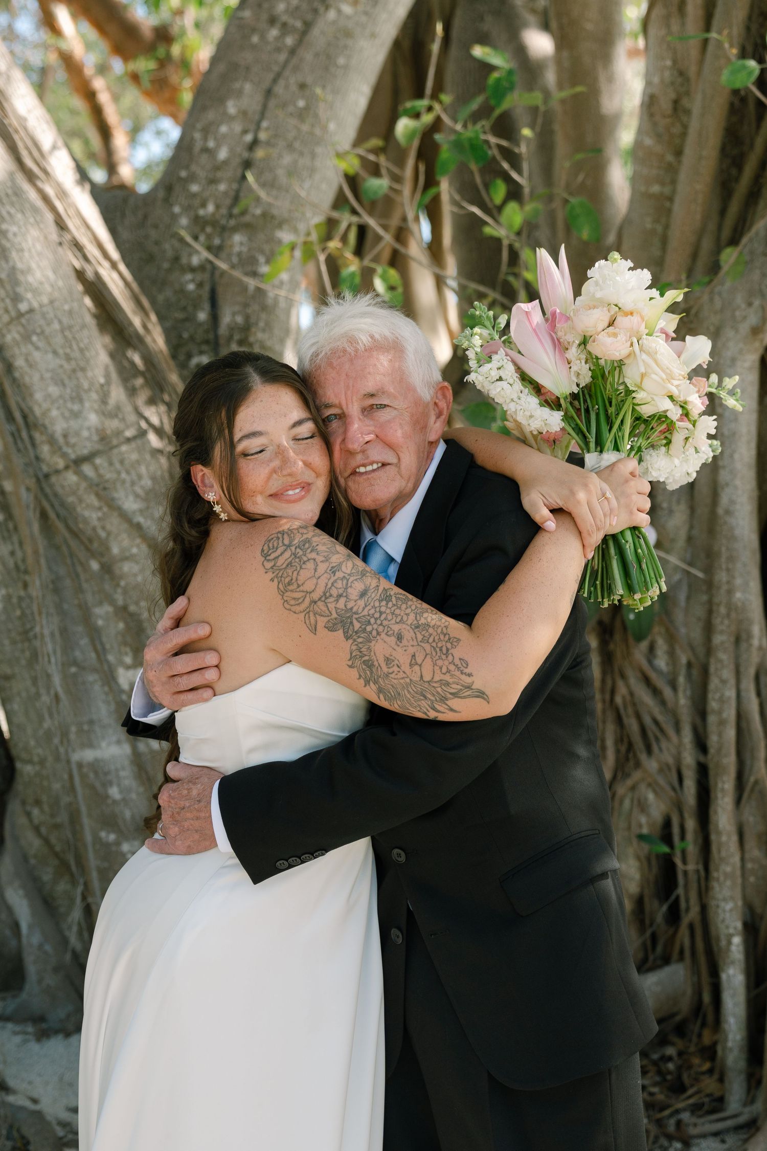 A group of people cheer and celebrate at a wedding on a beach.