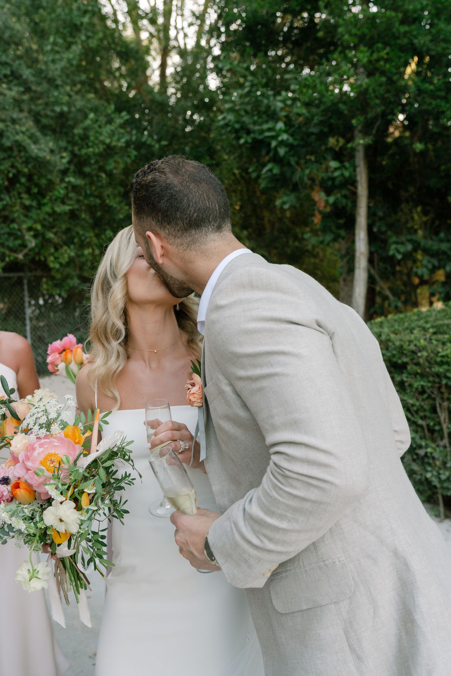 Romantic wedding moment with colorful bouquet against lush green background.