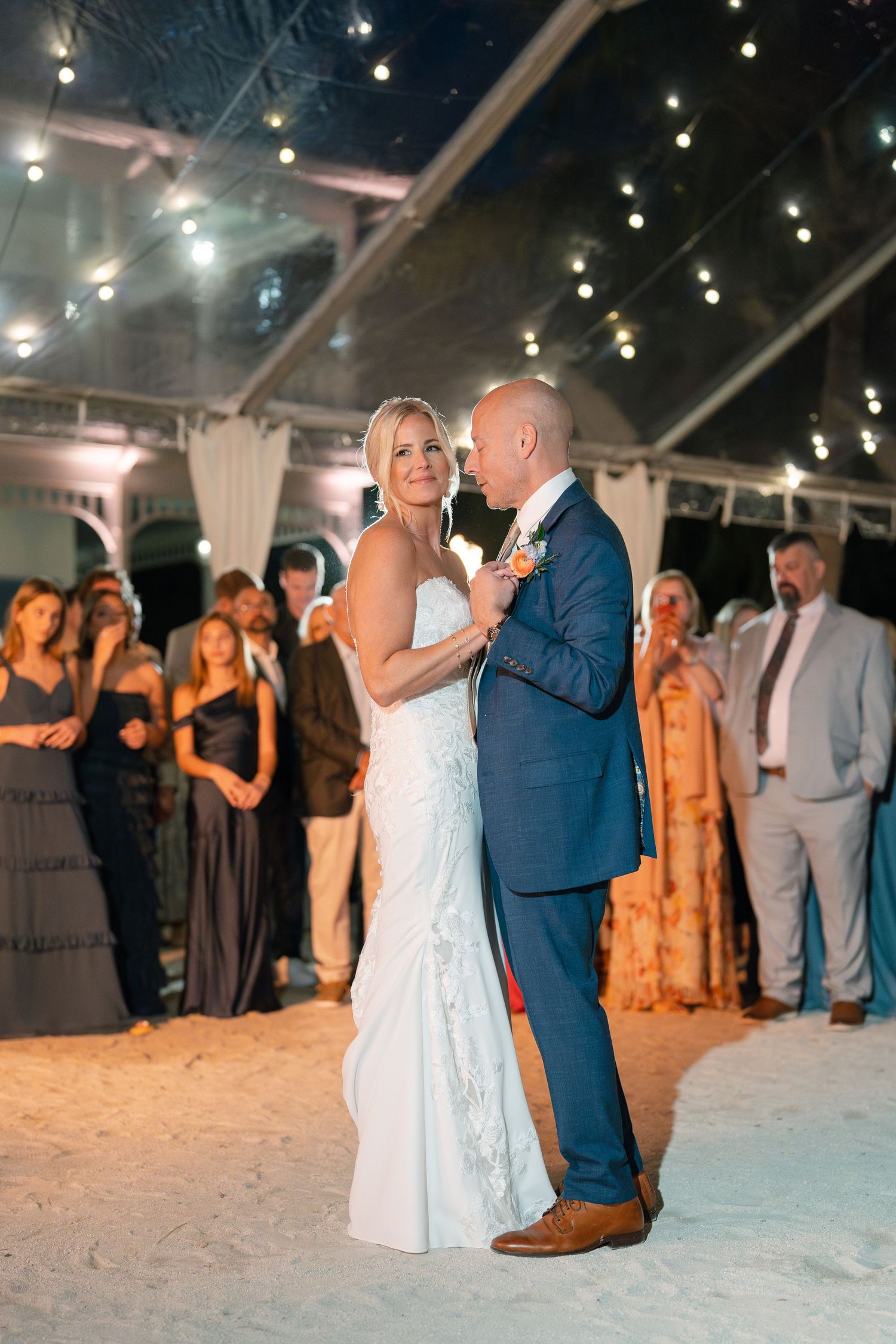 A couple shares their first dance under twinkling lights at their wedding reception.