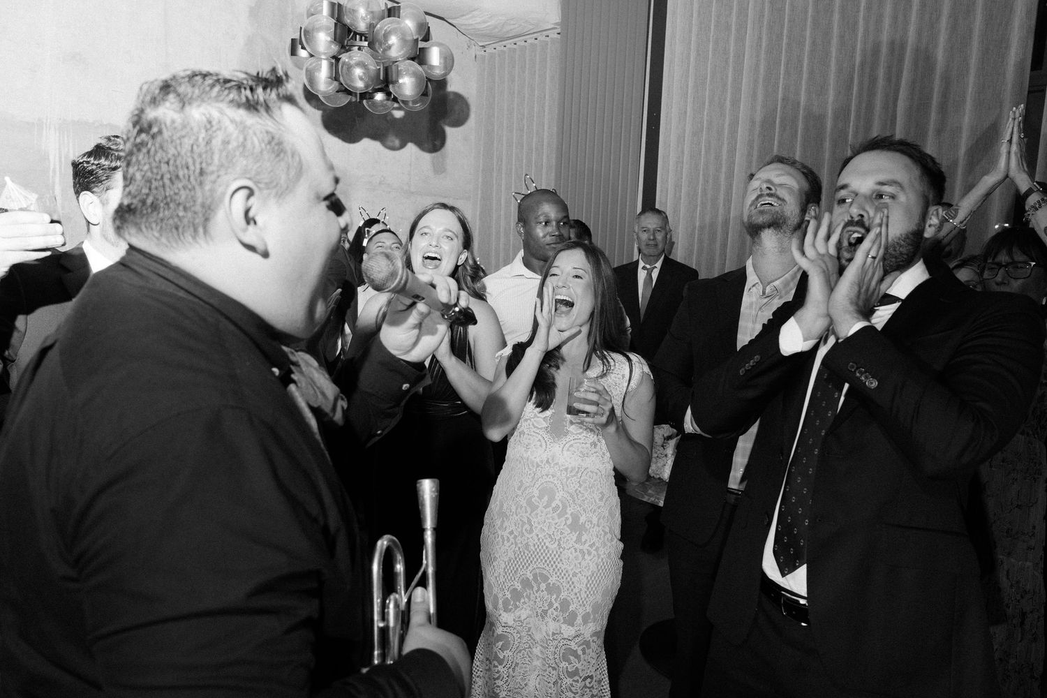 Wedding reception guests reacting with joy and excitement in candid black and white photos.