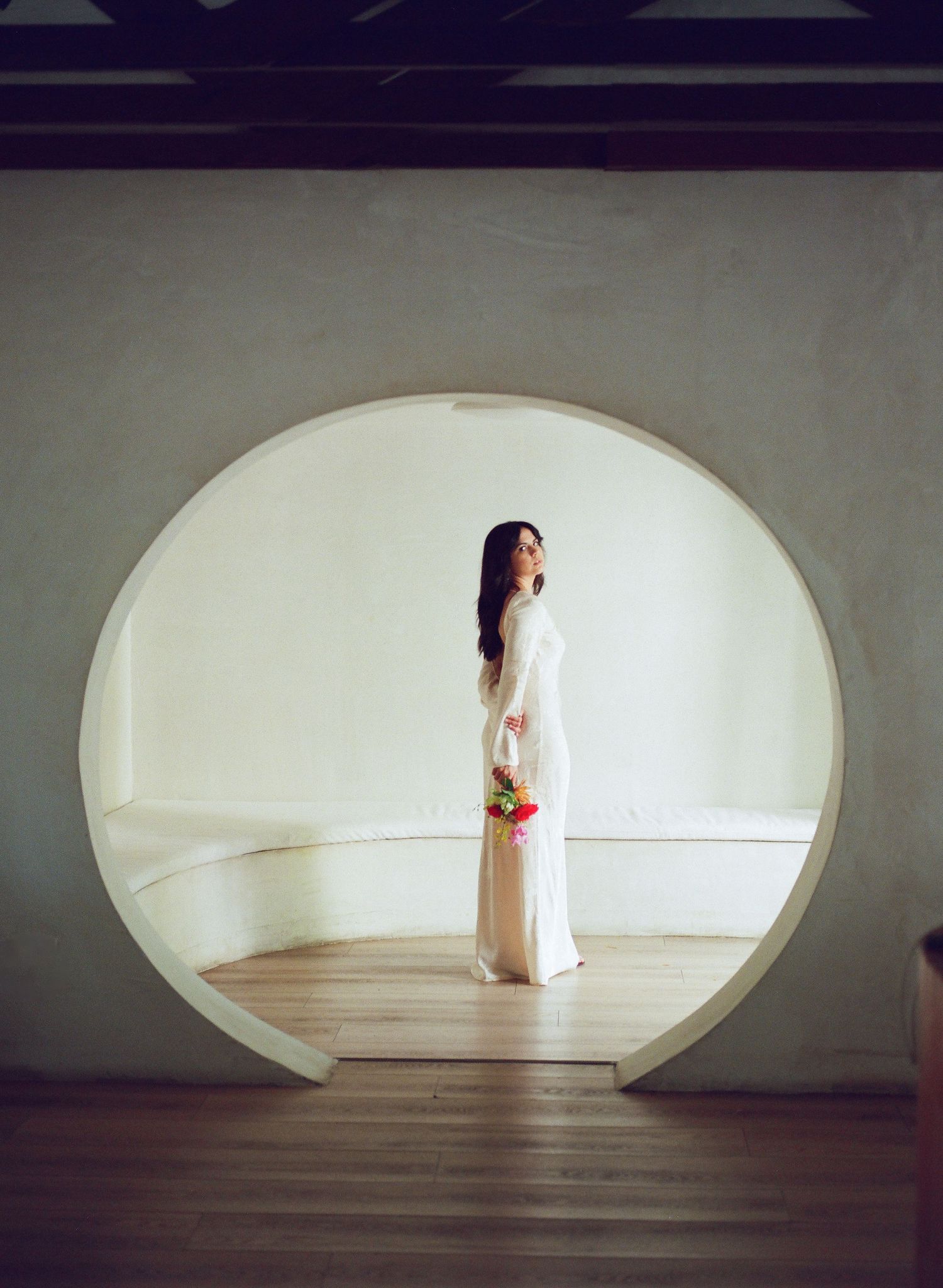 A minimalist architectural scene featuring a circular doorway and elegant white dress.