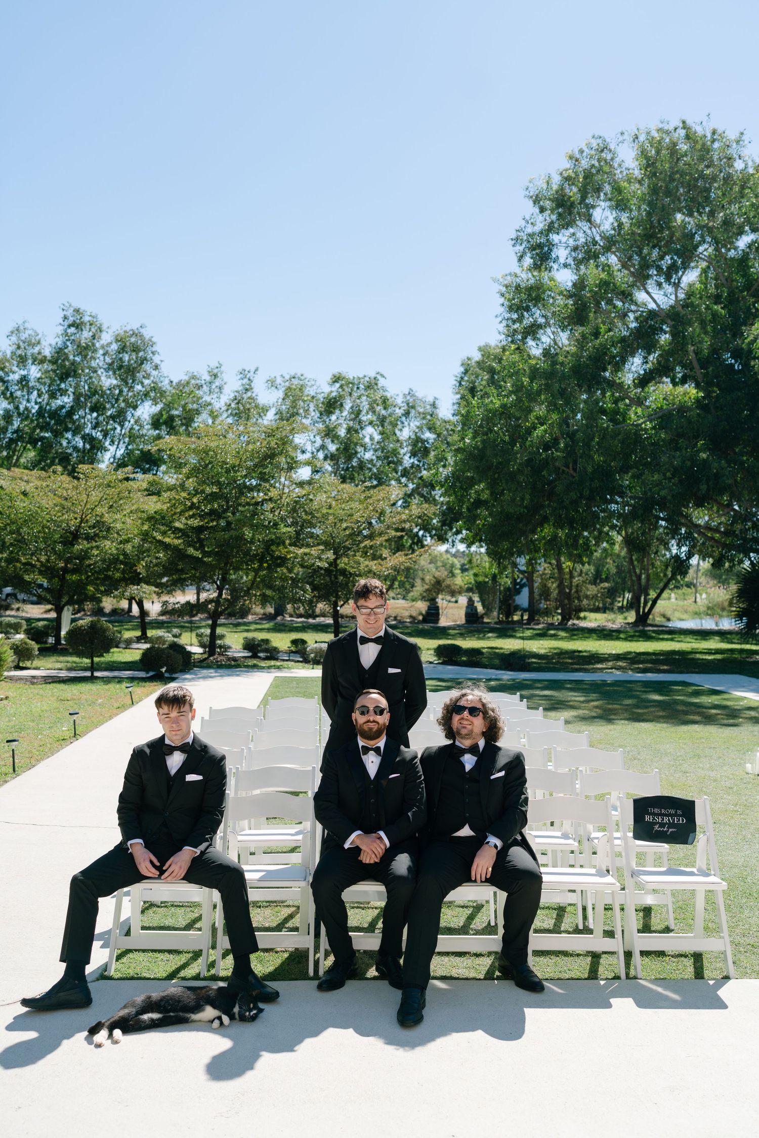 A group of people sitting on benches in a park surrounded by lush greenery.