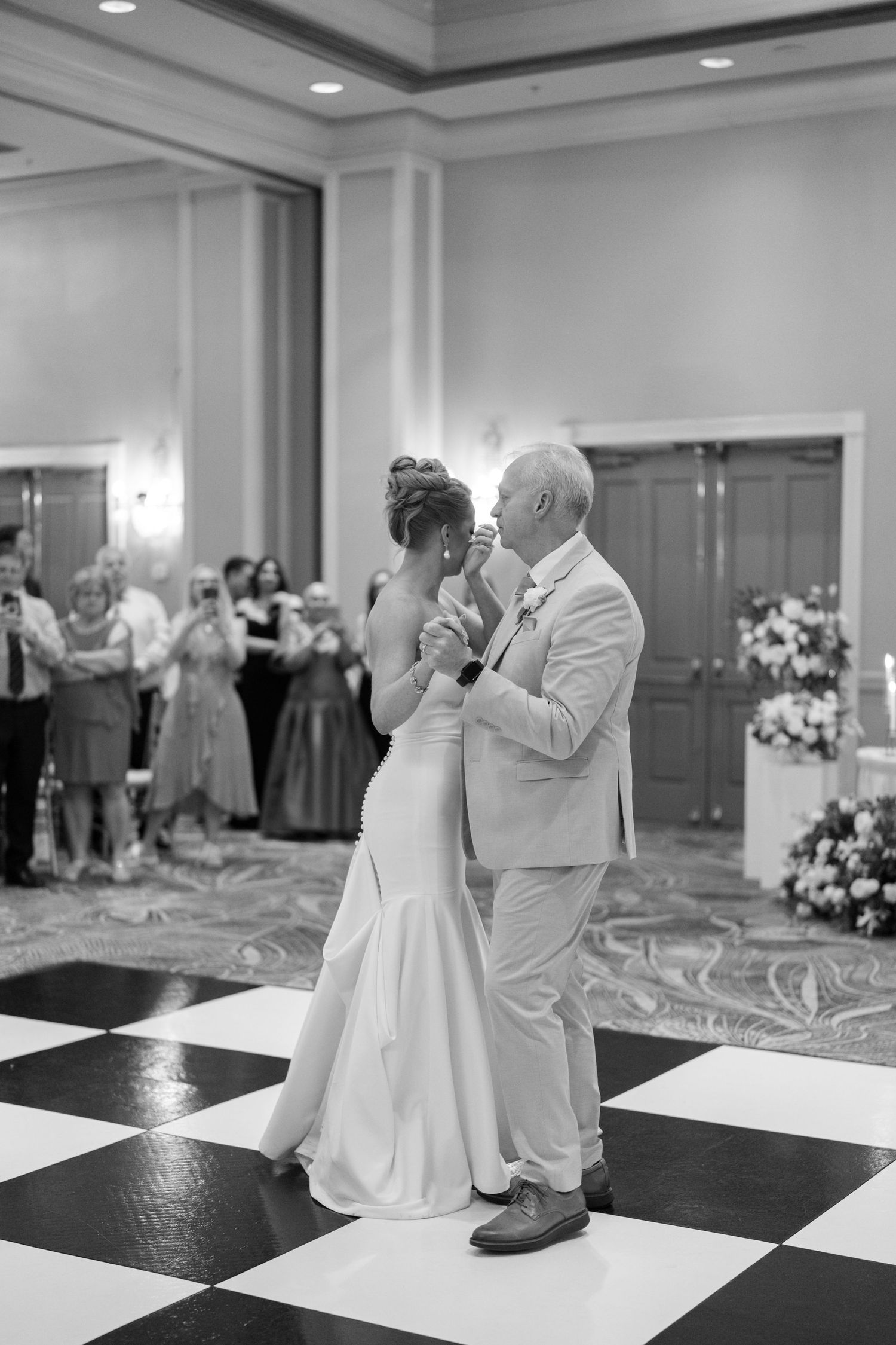 Black and white photo of a couple dancing on a checkered ballroom floor.