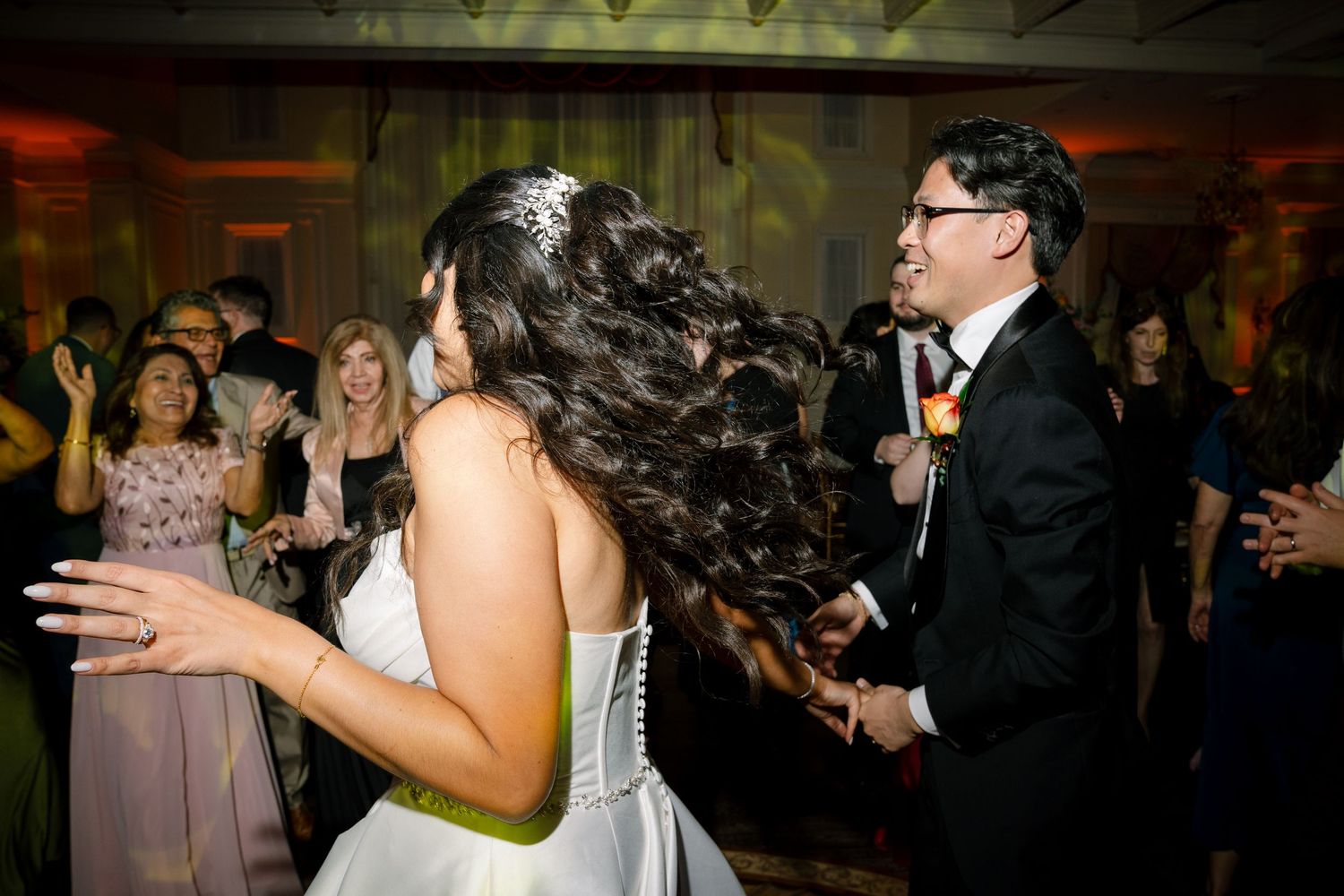 Newlyweds dancing together at their reception with guests visible in the background.