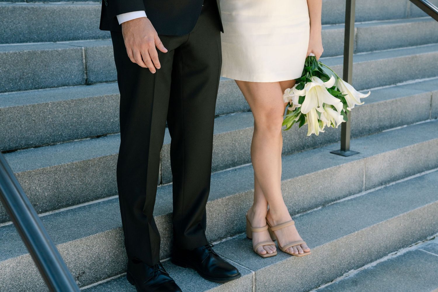 Wedding party members' feet and legs shown standing on stone steps during an outdoor ceremony.