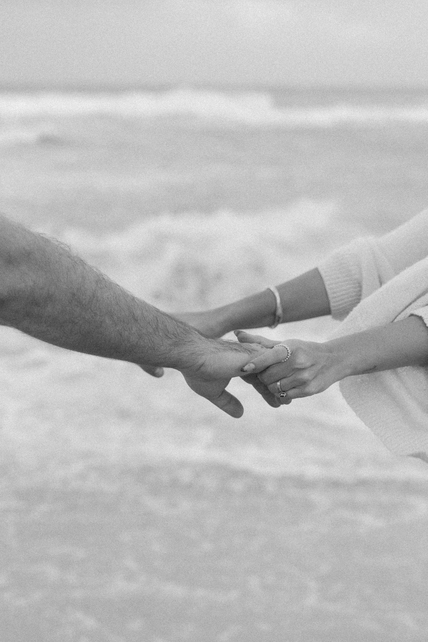 Black and white image sequence showing hands reaching and connecting in a minimalist artistic composition.