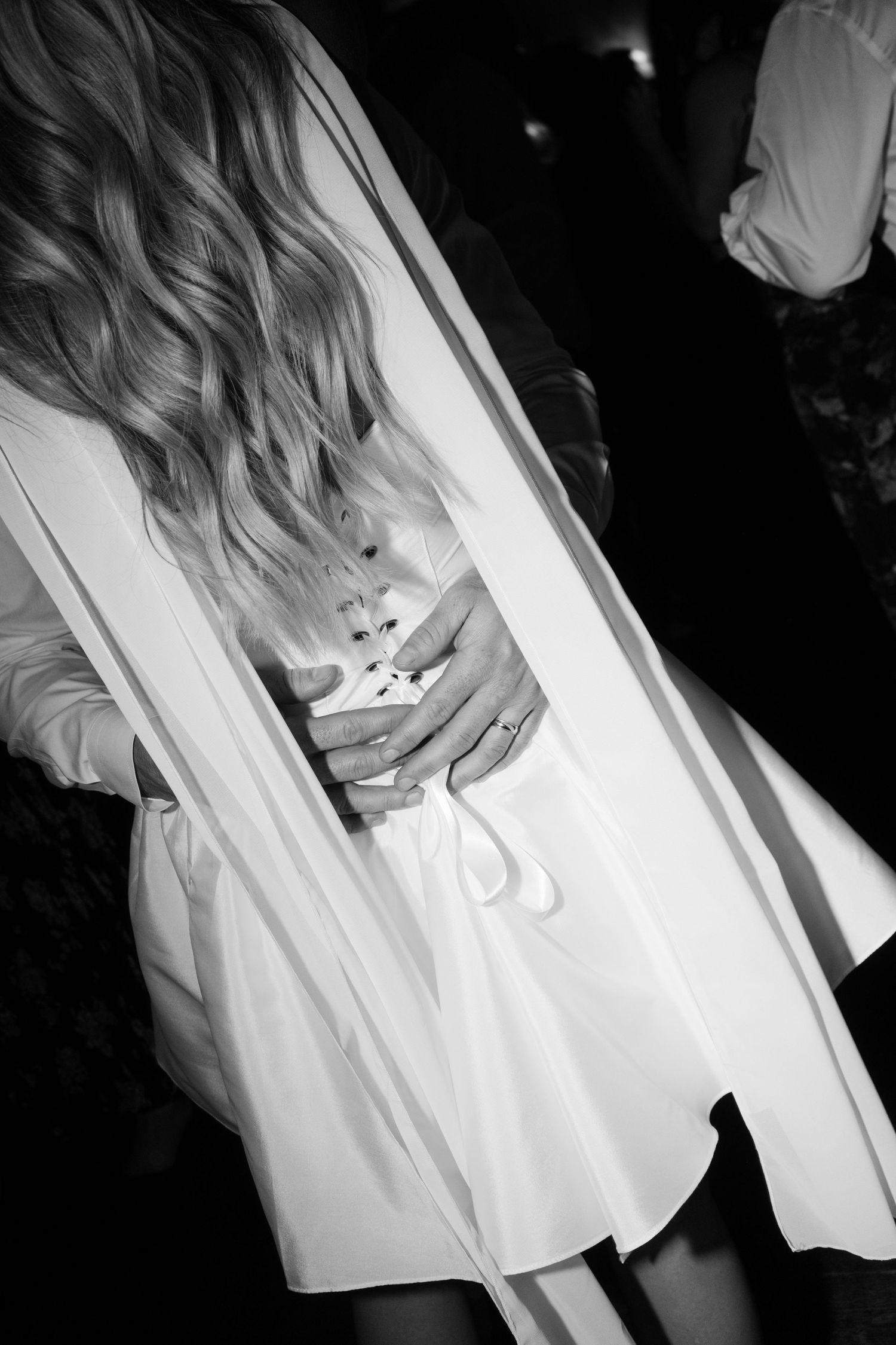 Black and white photo of bride holding bouquet with flowing veil and wavy hair.
