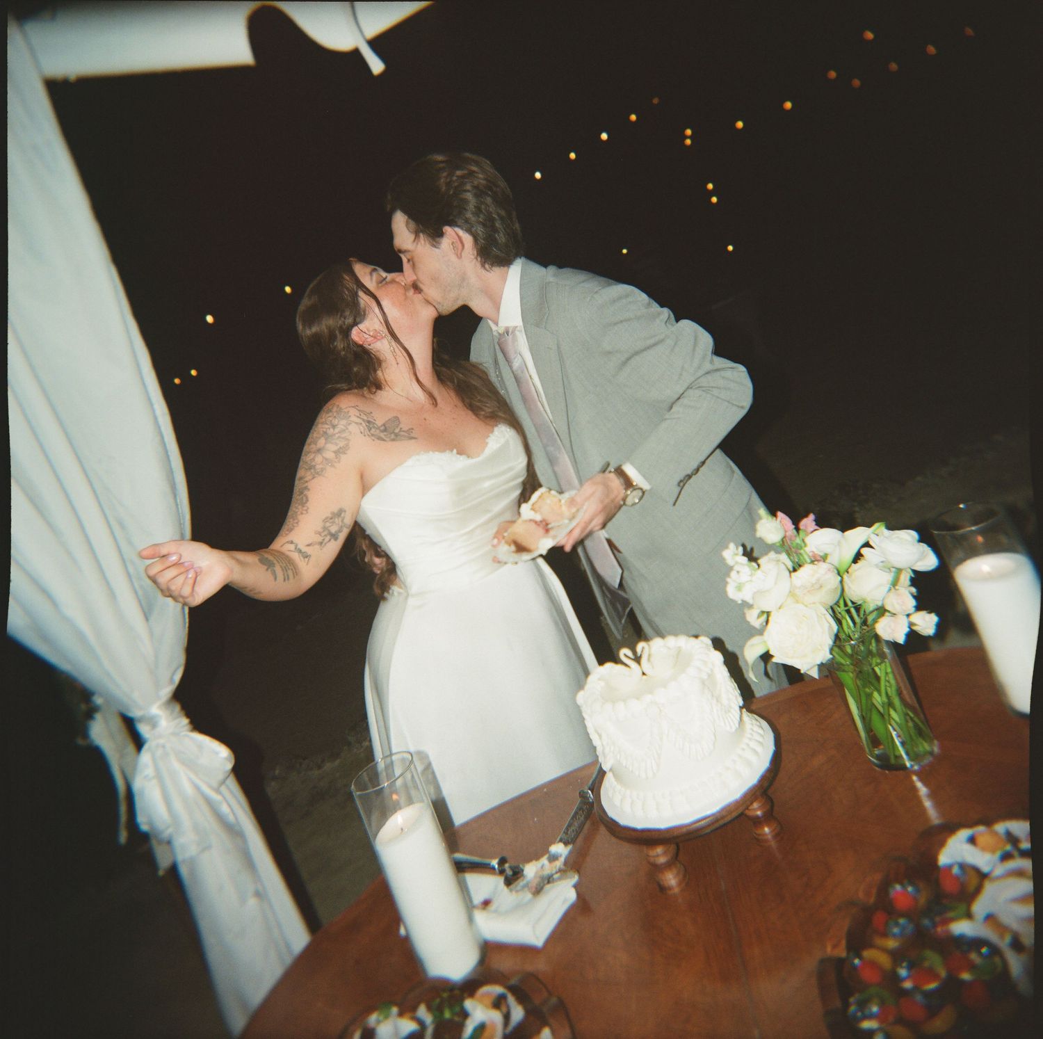 A bride and groom share a romantic moment on their wedding day, embracing and kissing on the dance floor.