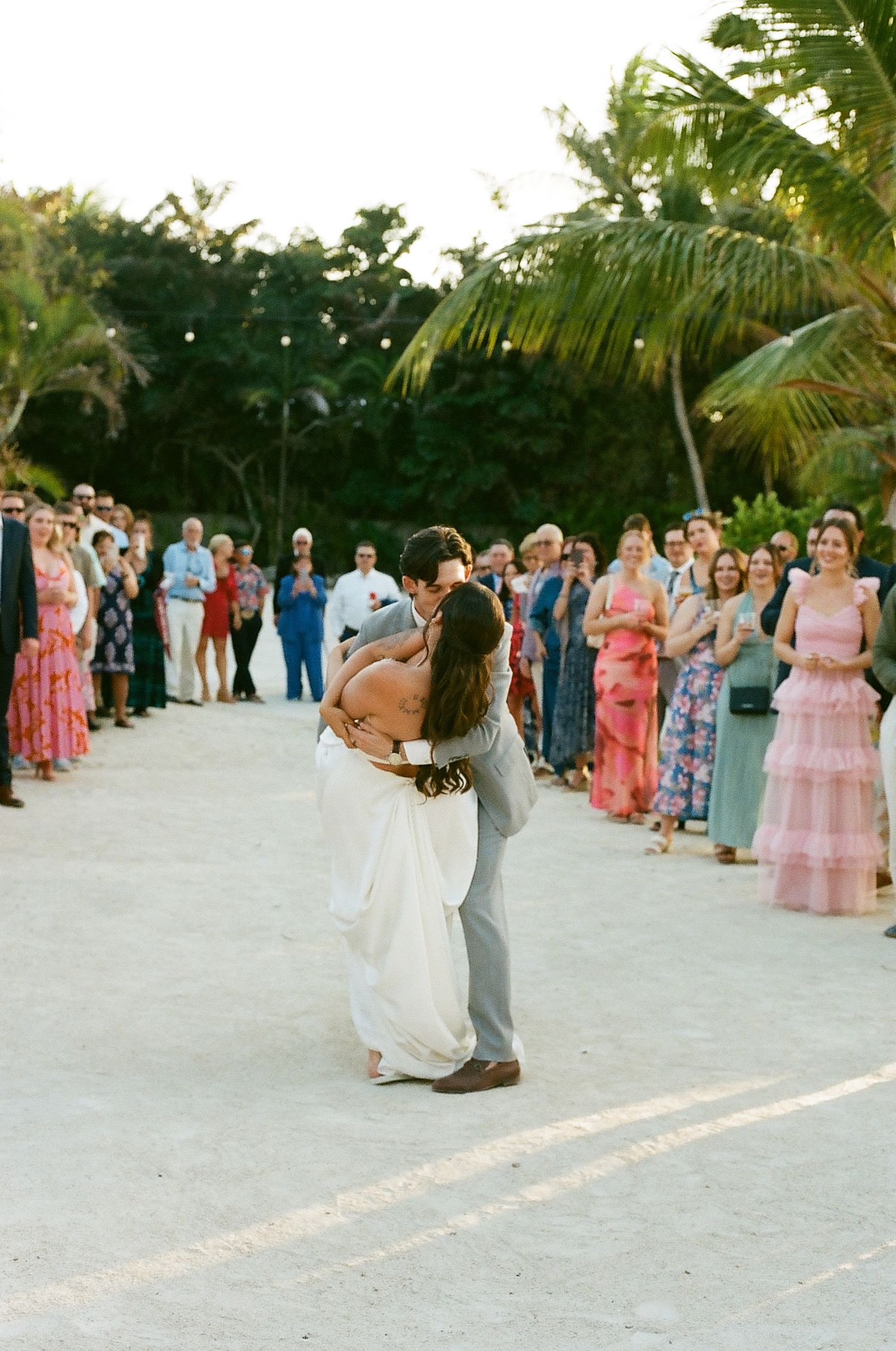 A bride and groom sharing a romantic dance at their wedding surrounded by guests.