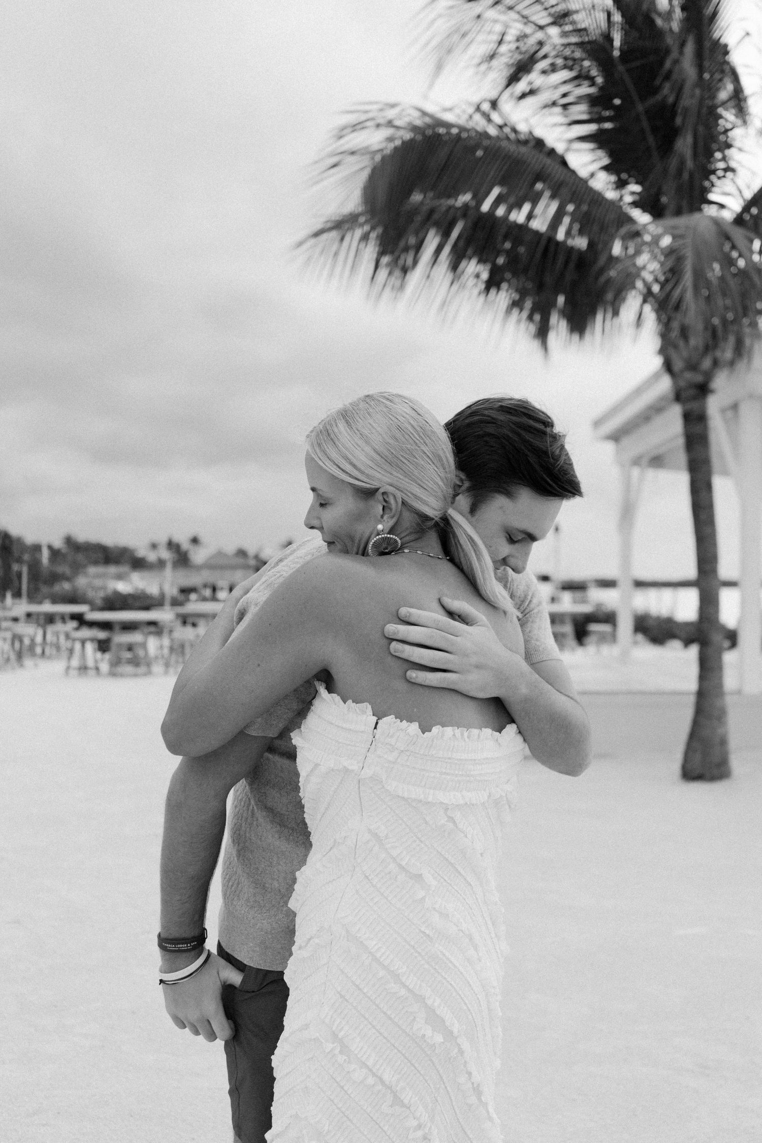 Black and white romantic beach photos showing intimate moments between a couple on a tropical beach with palm trees.