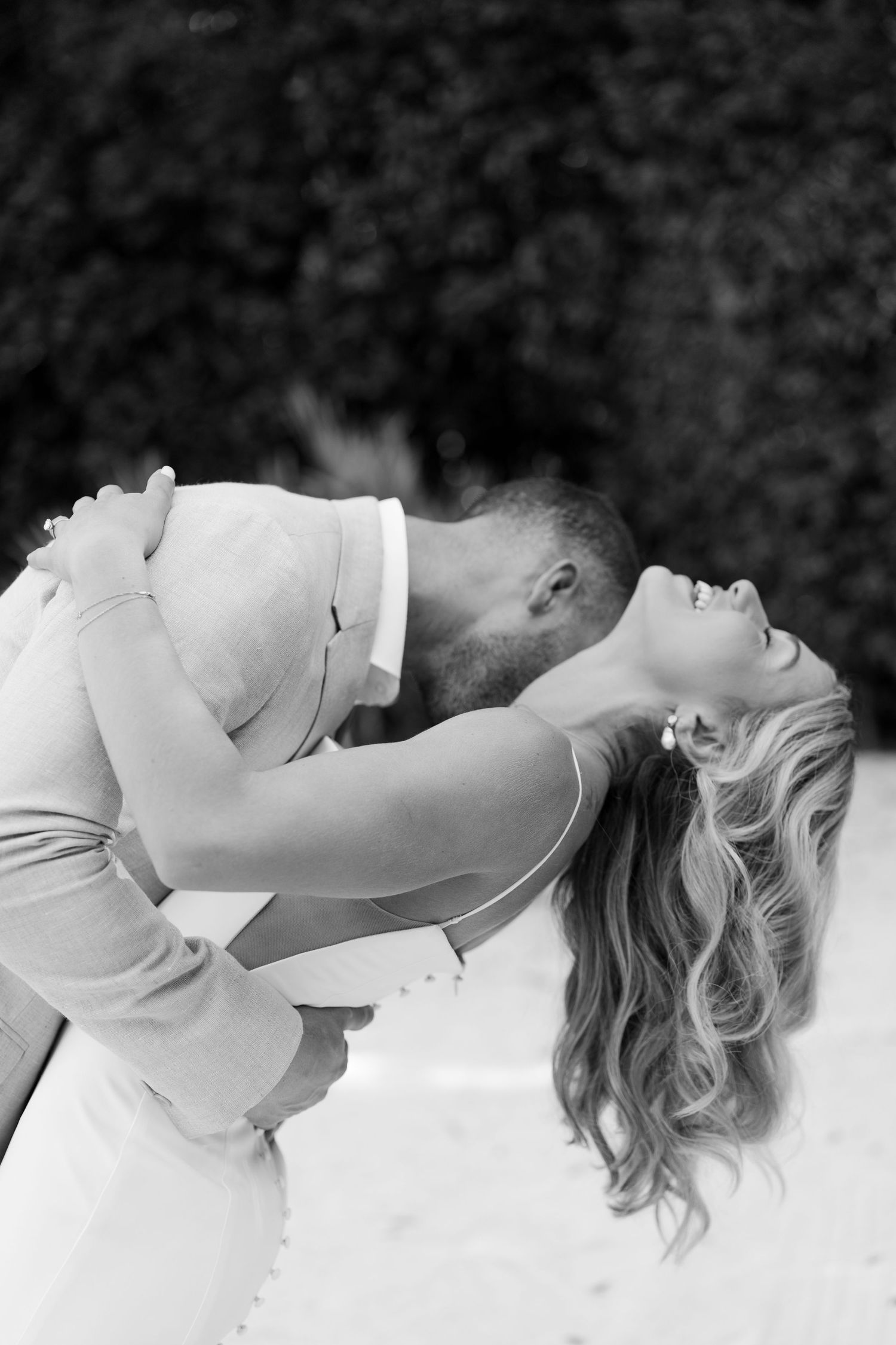 Black and white romantic photo sequence showing a couple in wedding attire embracing on a sandy beach.