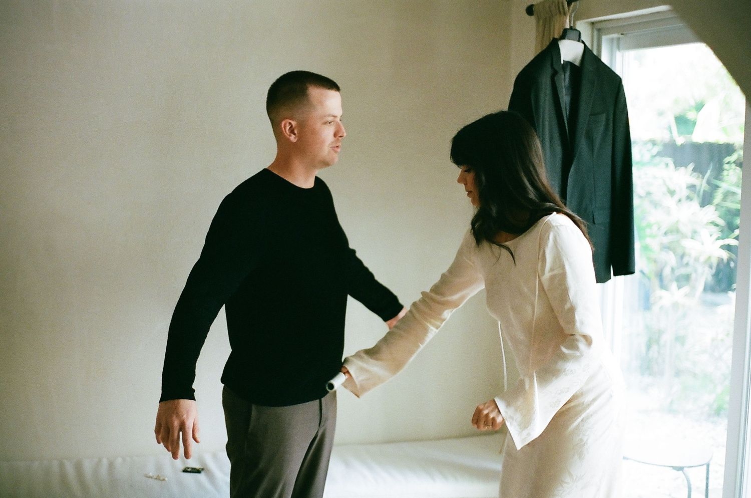 Two people practice martial arts moves in a bright indoor space with white walls.