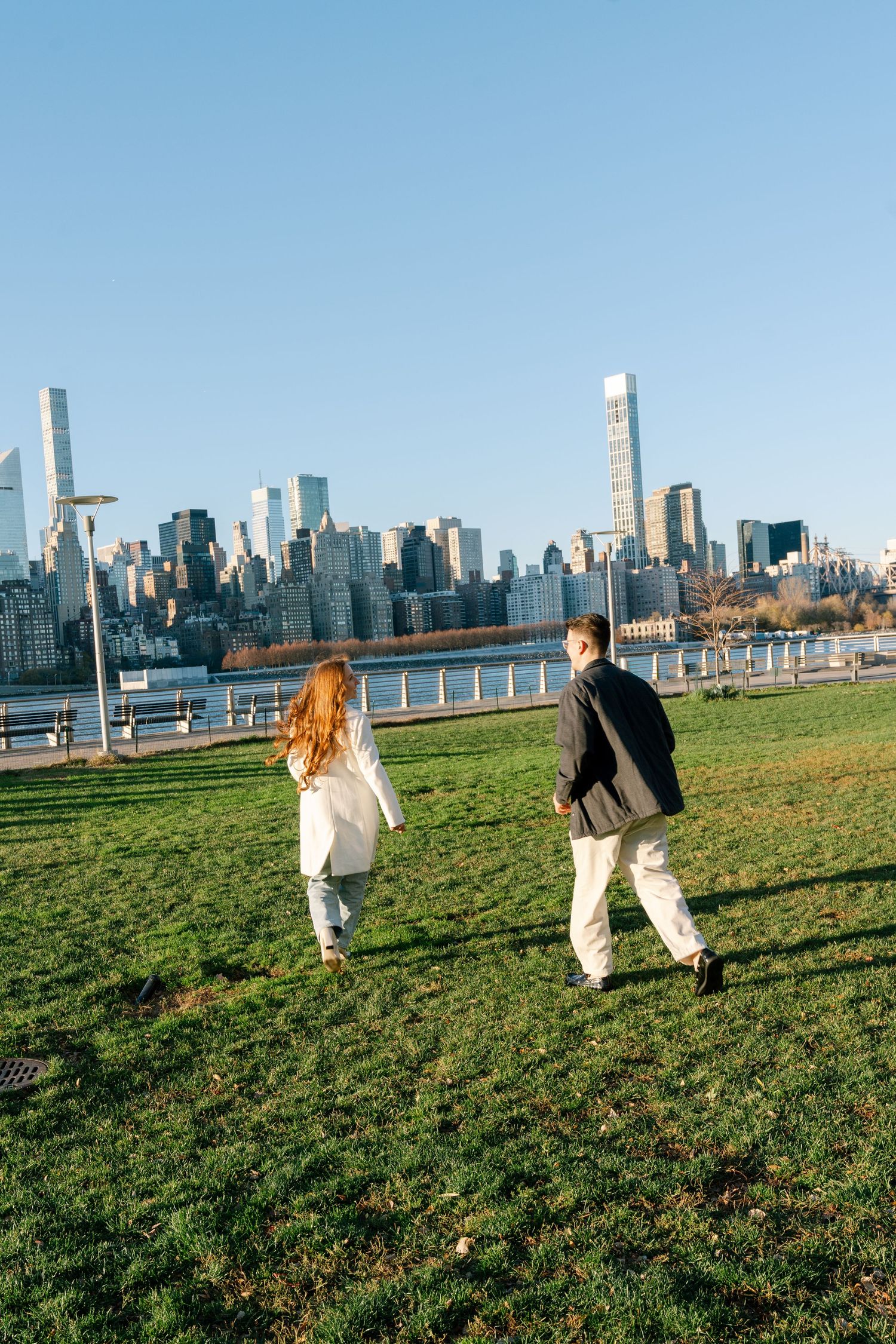 A playful sequence of running and chasing across a grassy field with the New York City skyline in the background.