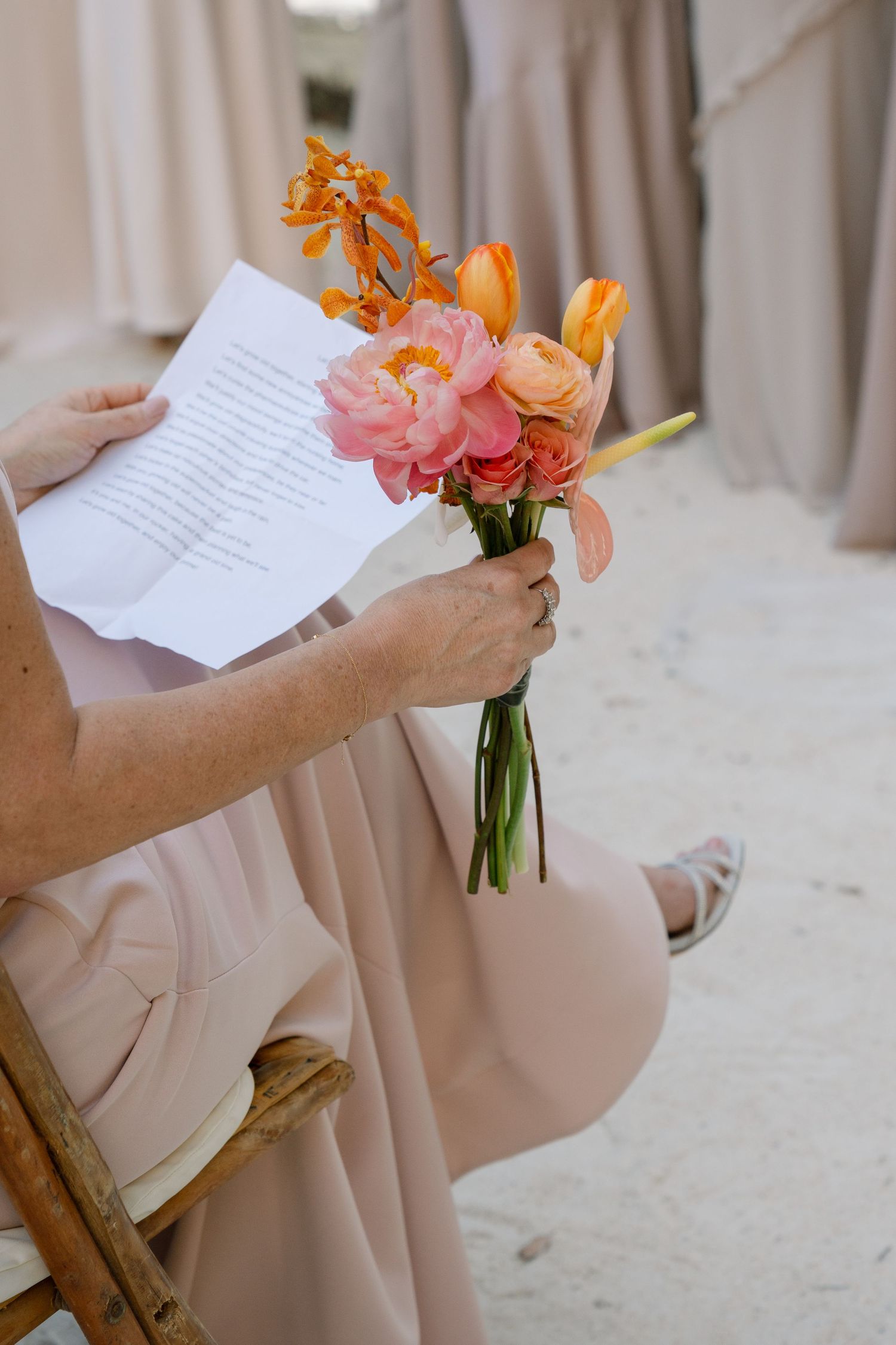 Hands holding a bouquet of orange and pink flowers with handwritten notes.