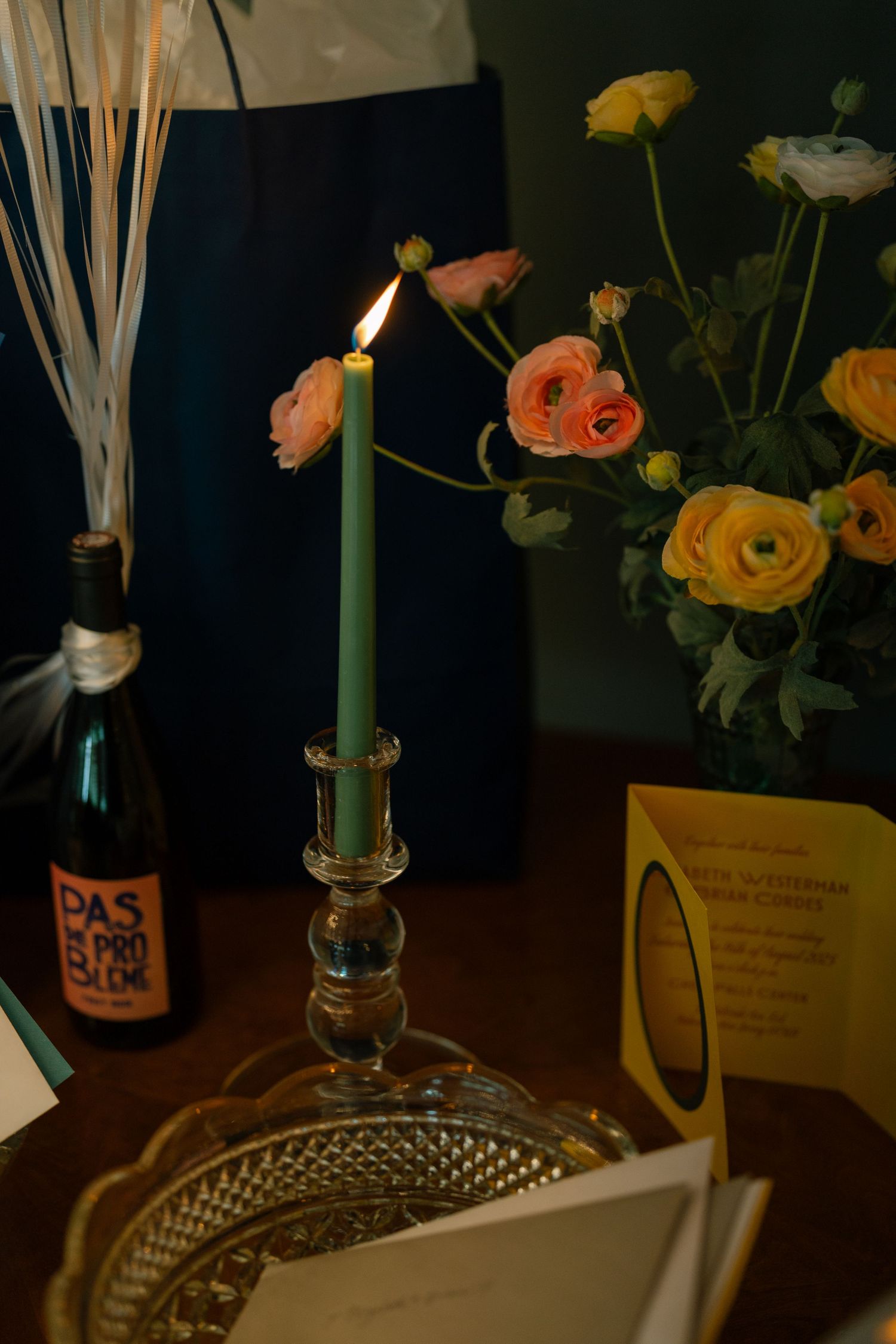 A series of moody candlelit vignettes with orange ranunculus flowers and green candles against a dark background.