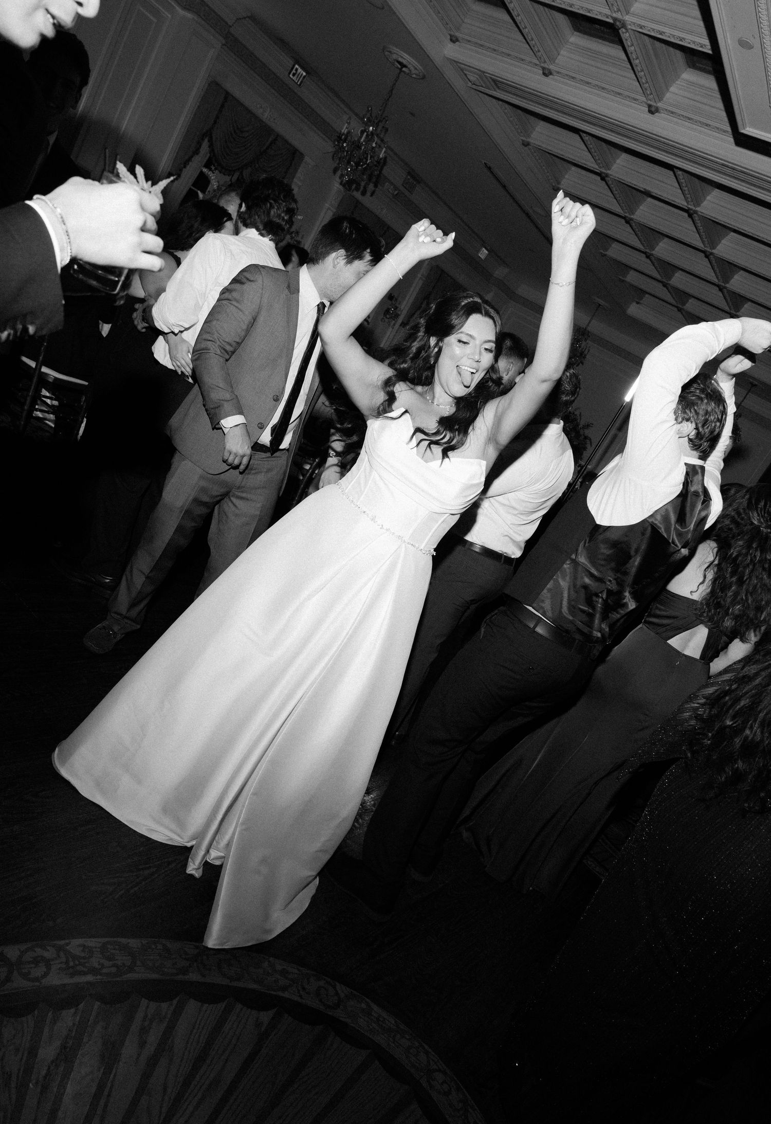 Wedding guests dancing and celebrating on a dark dance floor at an evening reception.