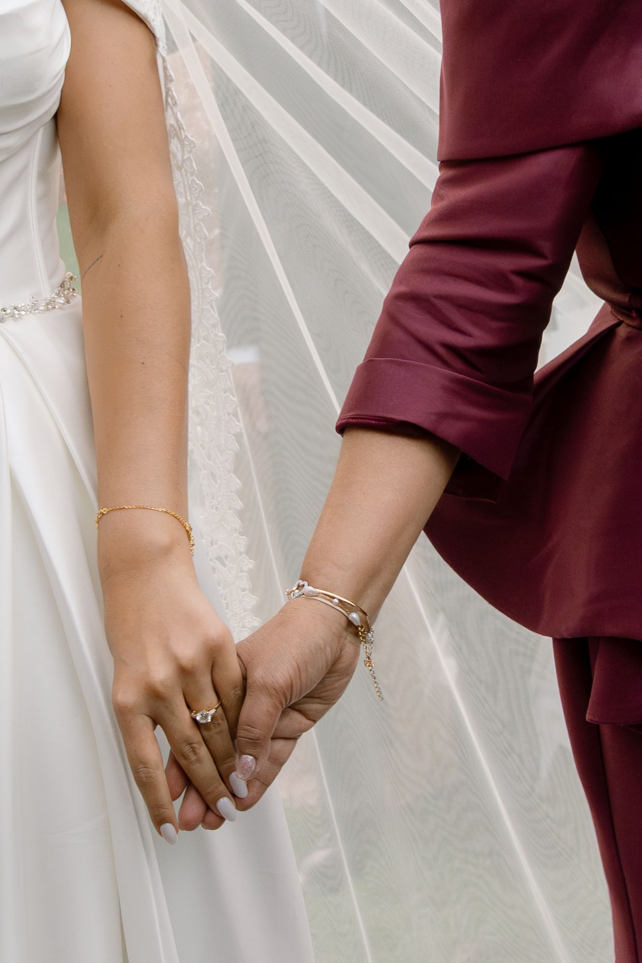 A series of close-up shots showing hands clasped together, with one person in white and another in burgundy attire.