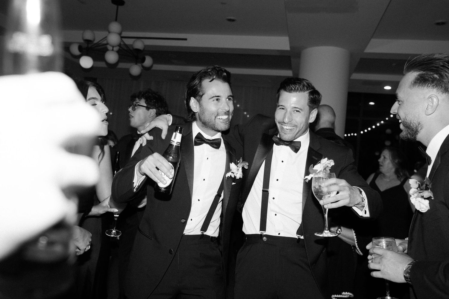 Wedding reception guests in formal black tie attire mingling at an evening celebration.