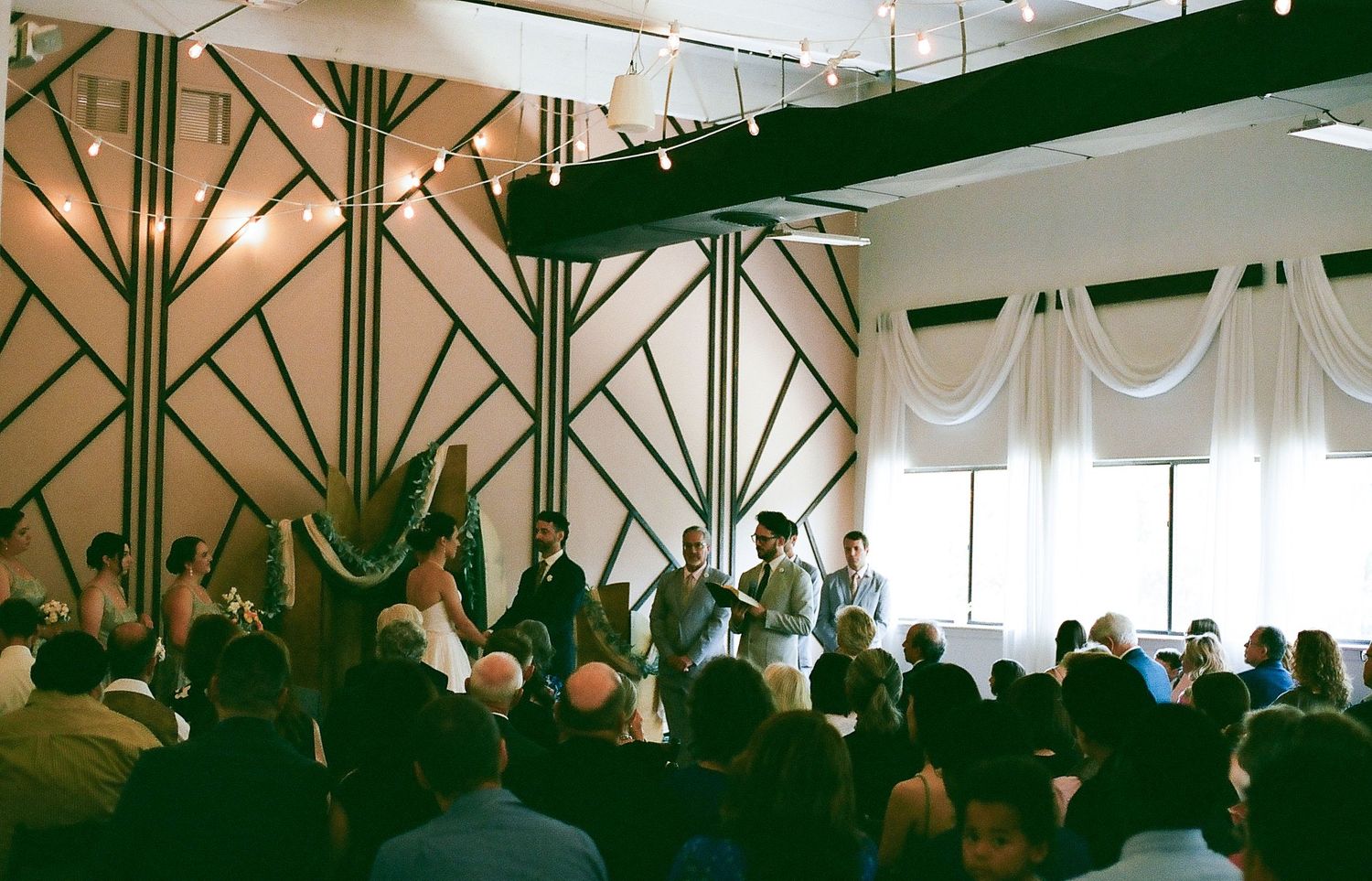 A dimly lit wedding reception venue with tables and chairs set up for guests under decorative lighting.
