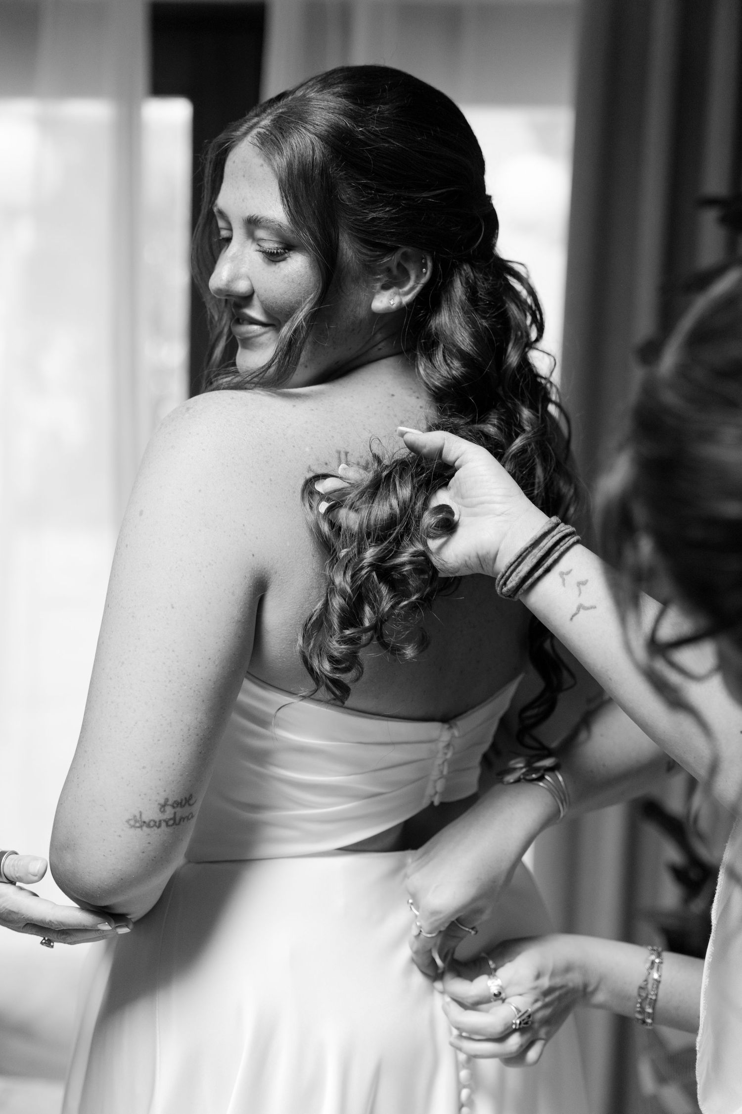 A woman with long, dark hair smiles and looks away from the camera.