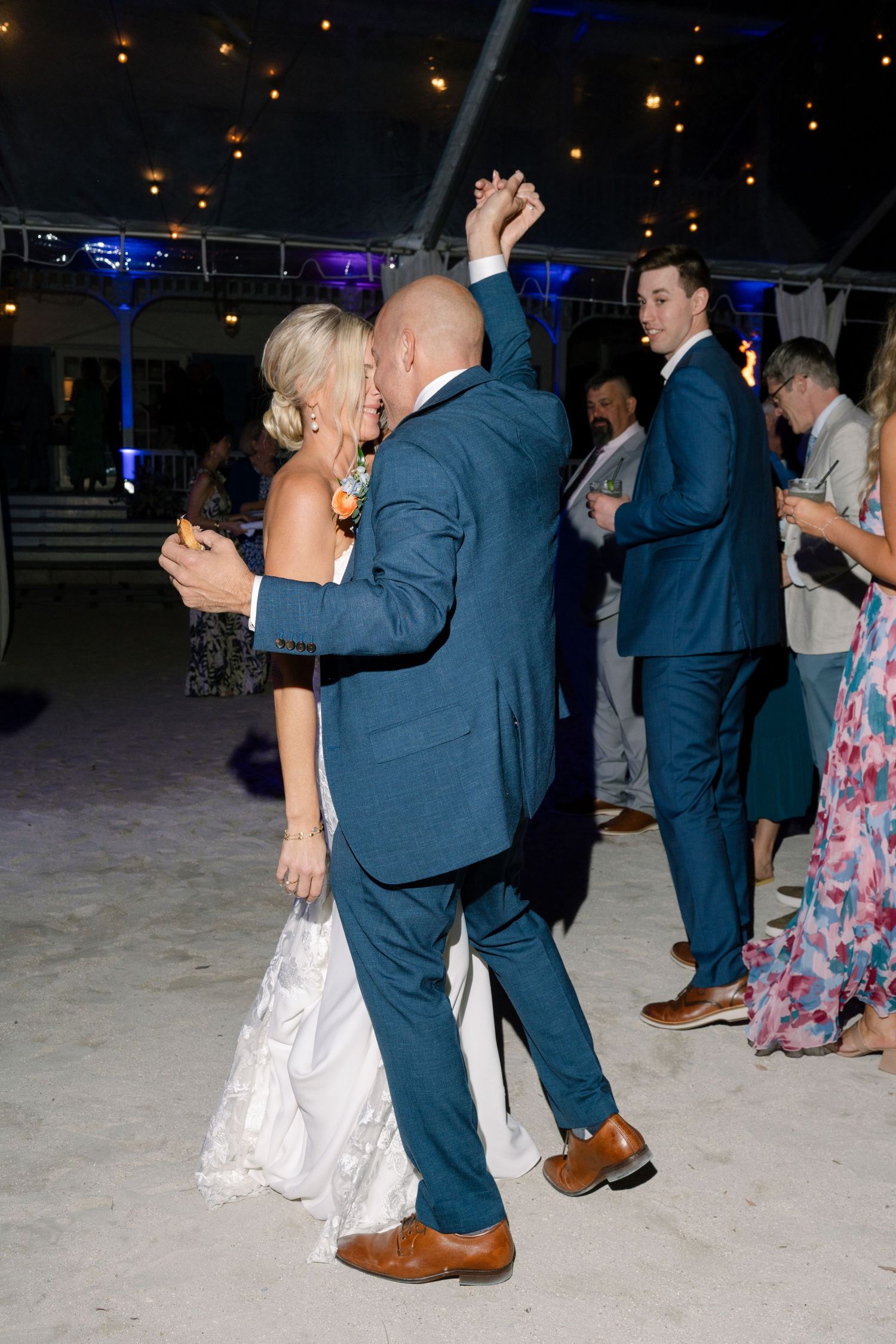 Couples dancing on the beach at night during a wedding reception.
