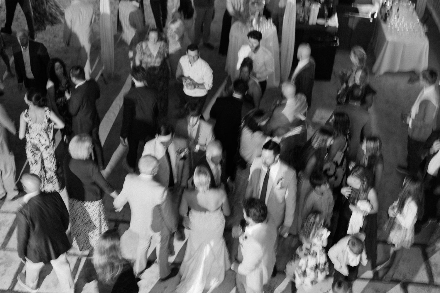 A large crowd of people dancing and celebrating at a lively black and white party or social gathering.