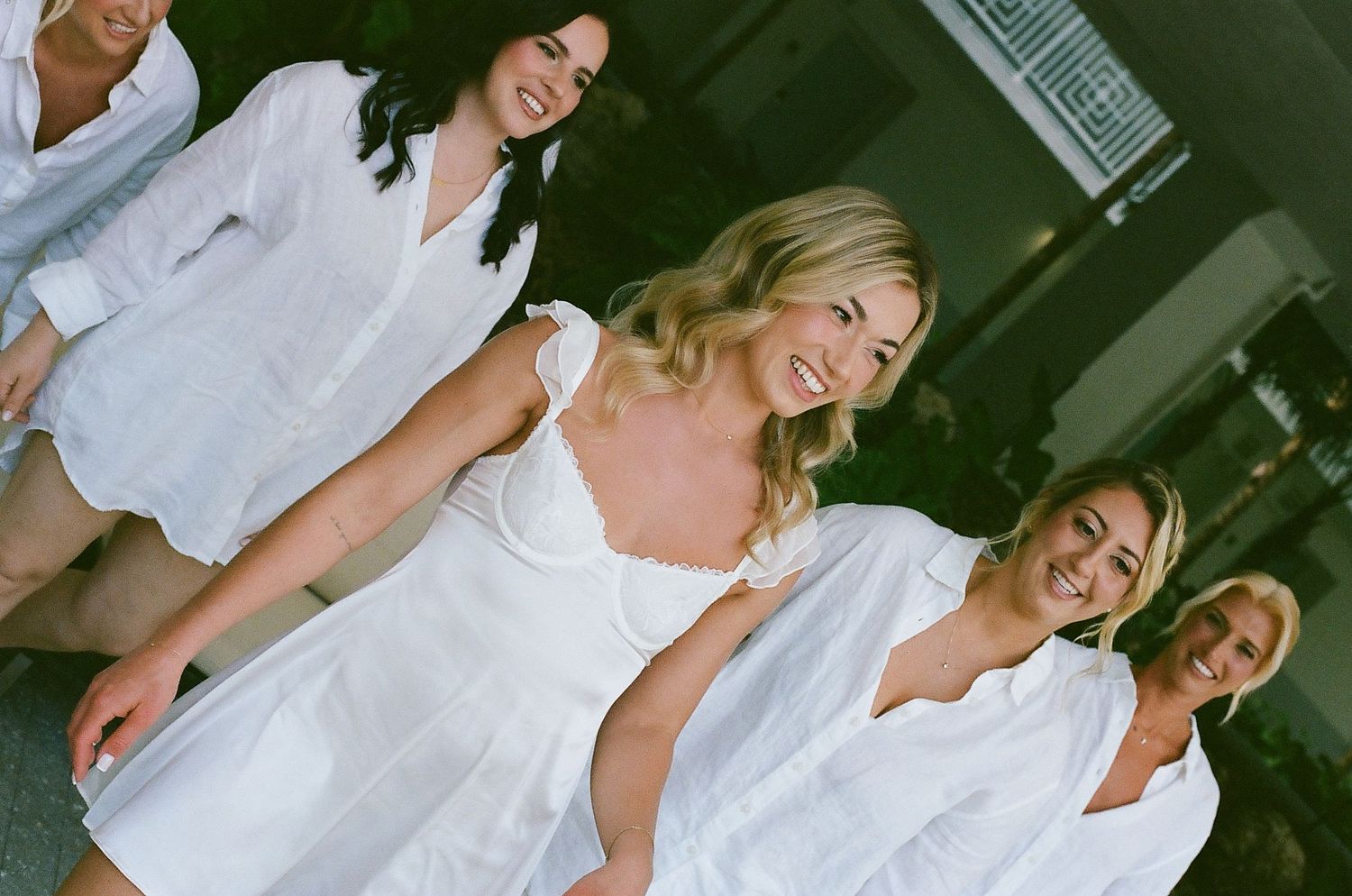 Group poses in coordinated white outfits during a sunny outdoor celebration.