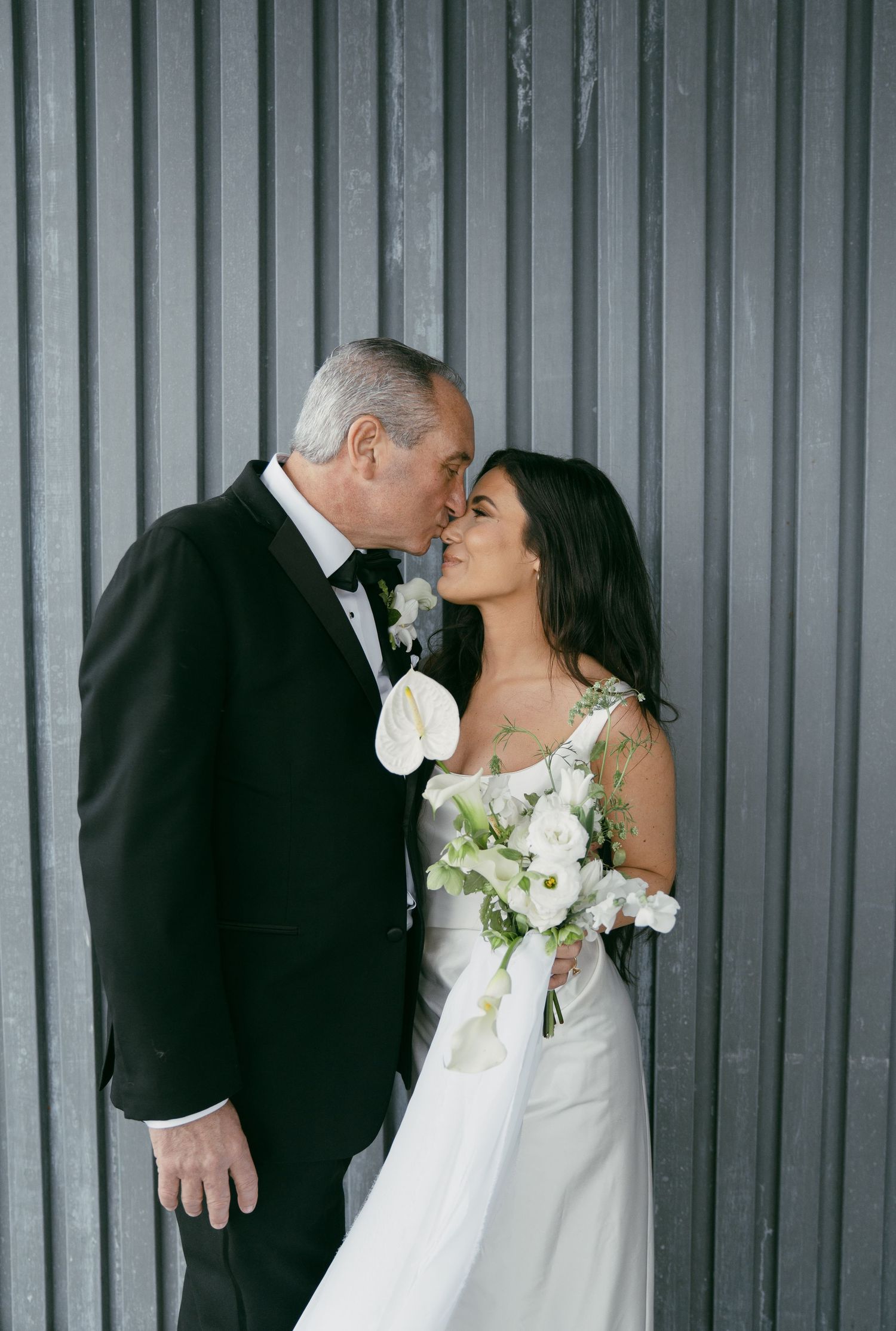 Romantic wedding portraits against an industrial corrugated metal wall backdrop.