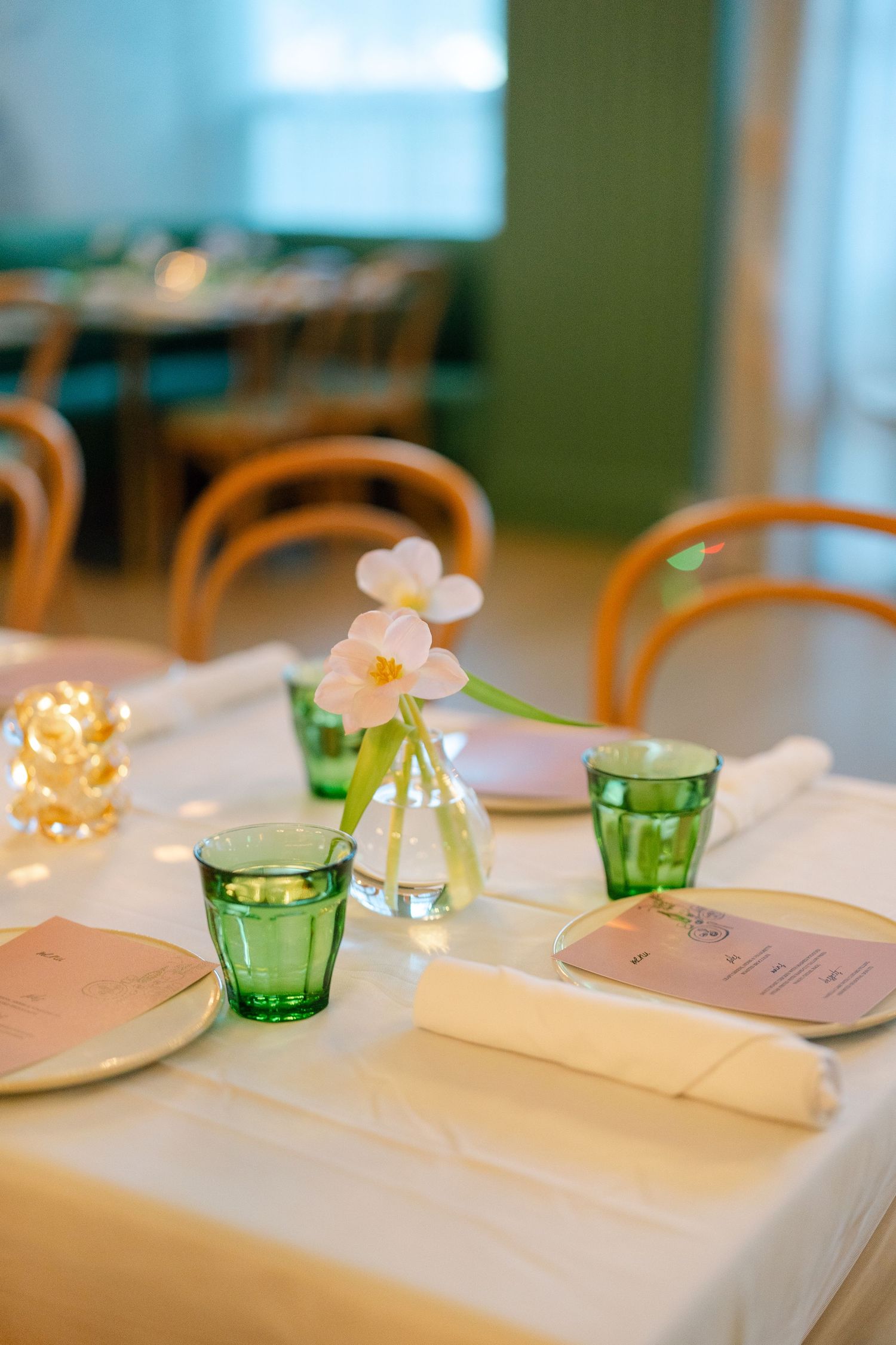 Table settings with pink and green glassware and delicate floral decorations for a special event.