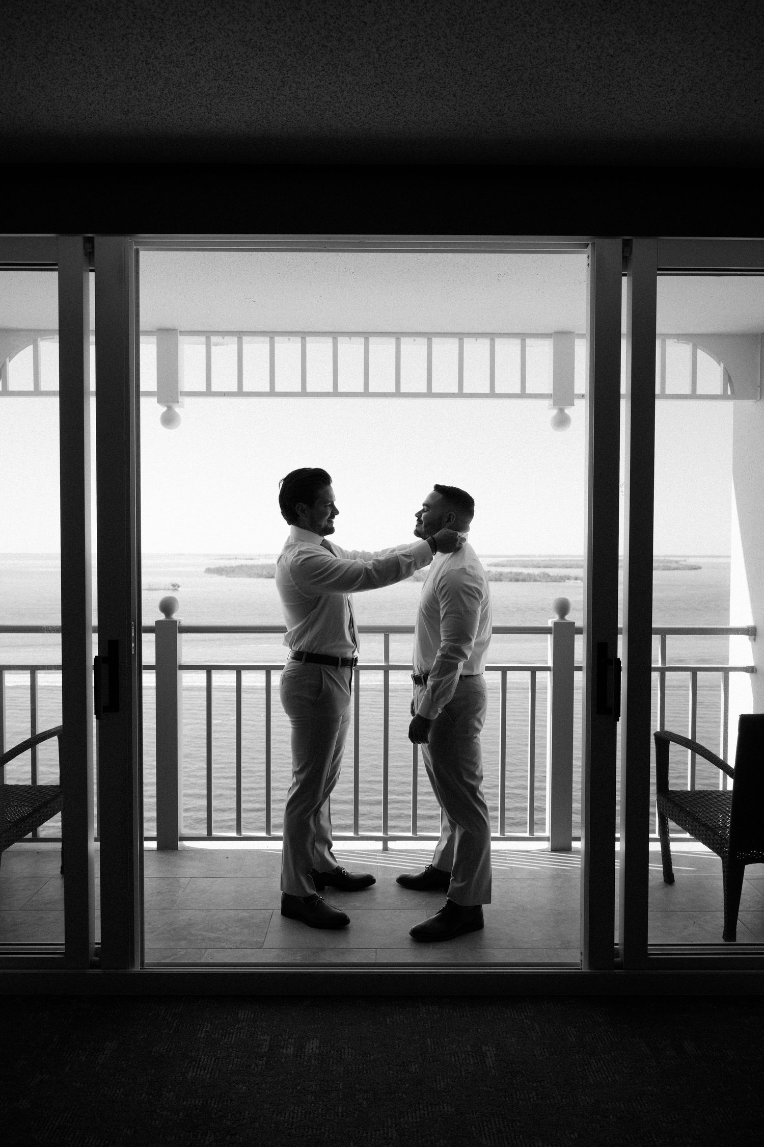 Silhouetted figures stand against bright windows in a modern building, creating a dramatic black and white composition.