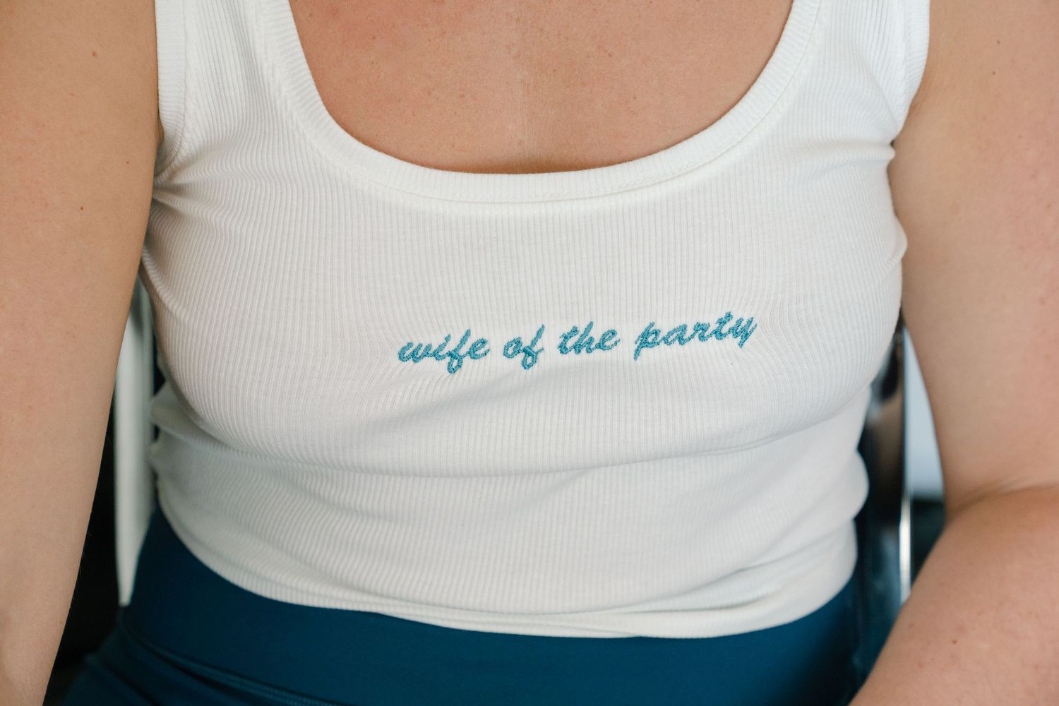 Five women in white tank tops pose together with text 'wife of the party' visible on one shirt.