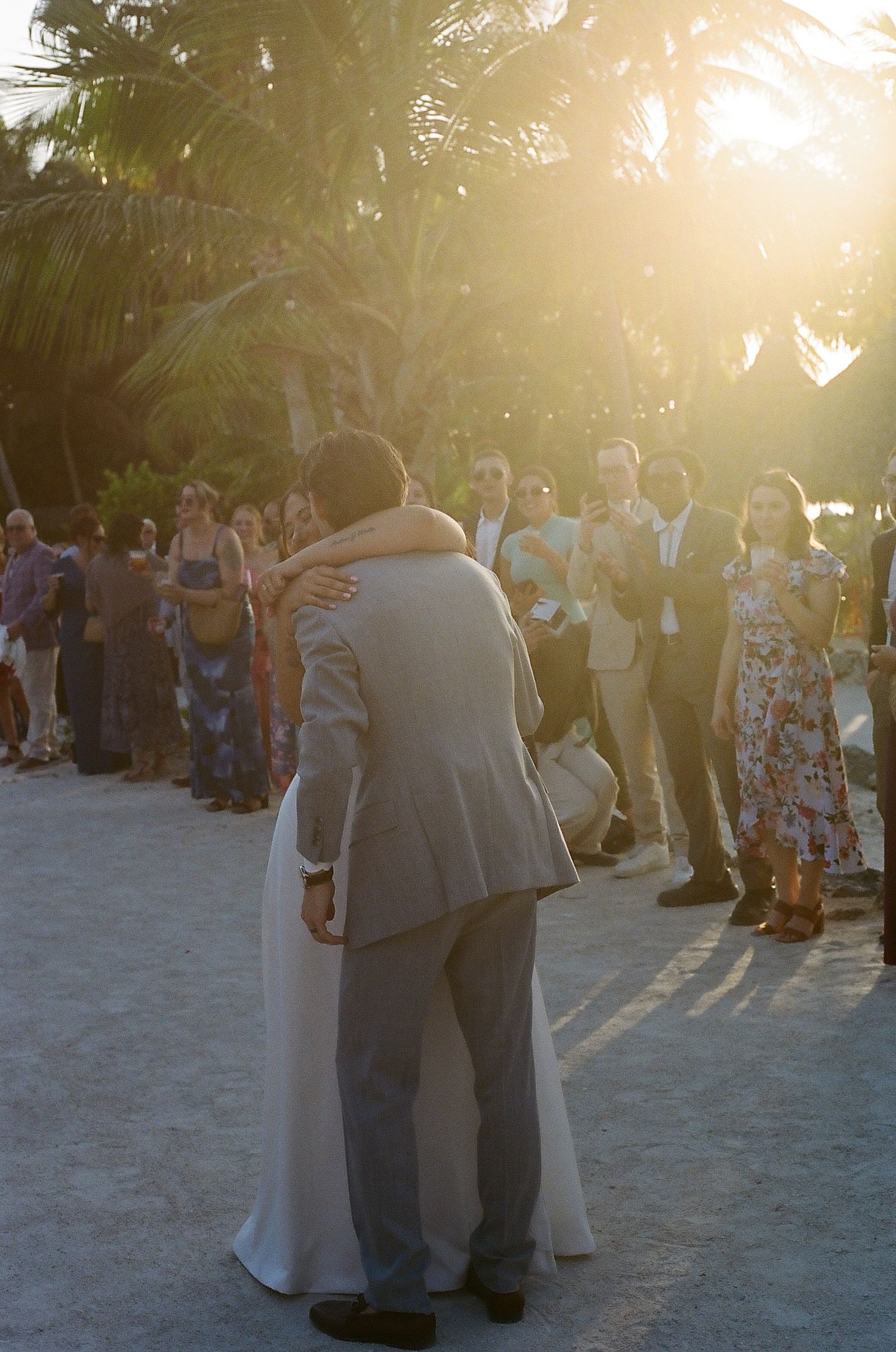 A group of people are gathered in a tropical setting, enjoying the sunset and each other's company.