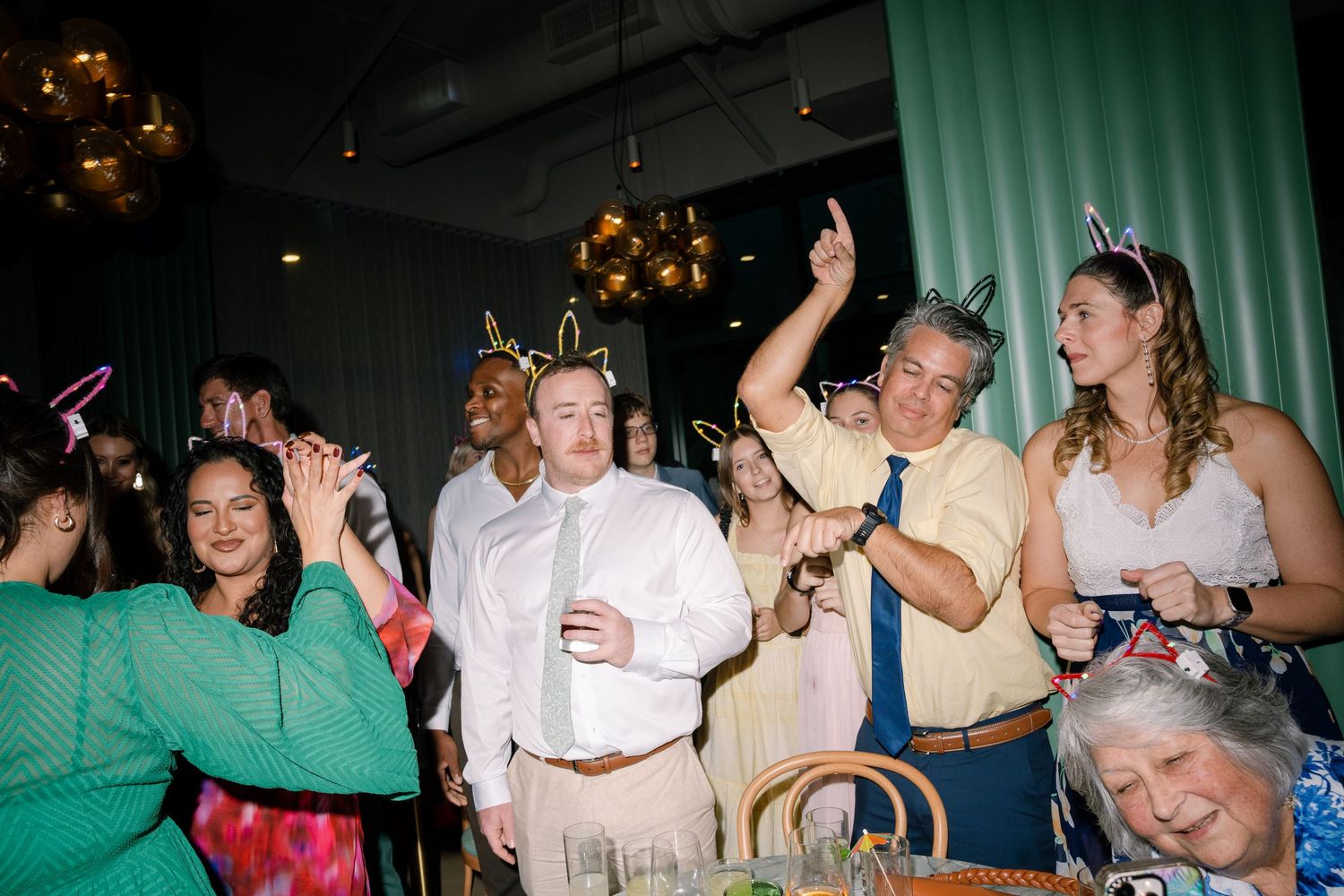 Lively dance floor scene at wedding reception with guests in formal attire.