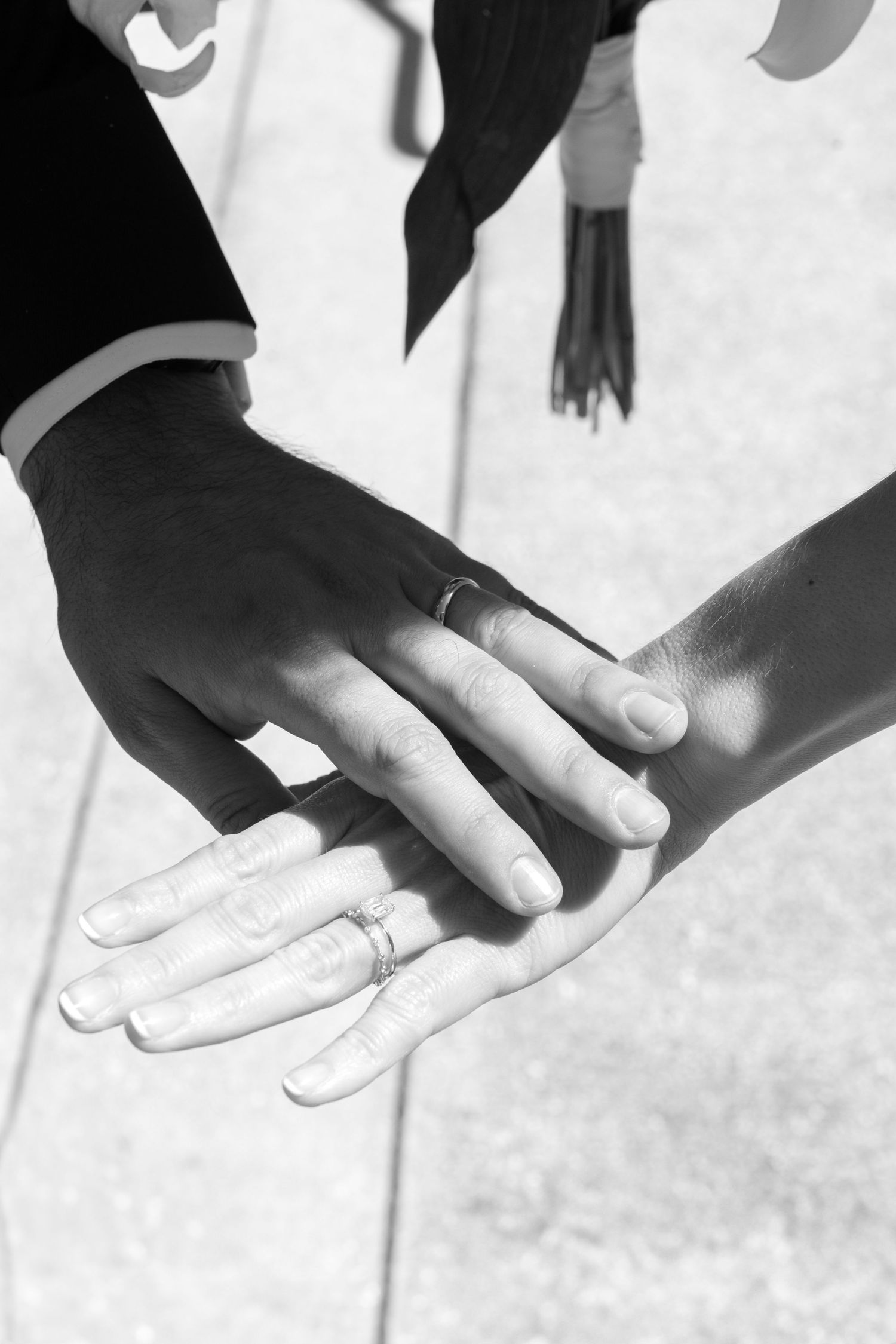 Close-up sequence of hands showing wedding ring exchange in black and white photography.