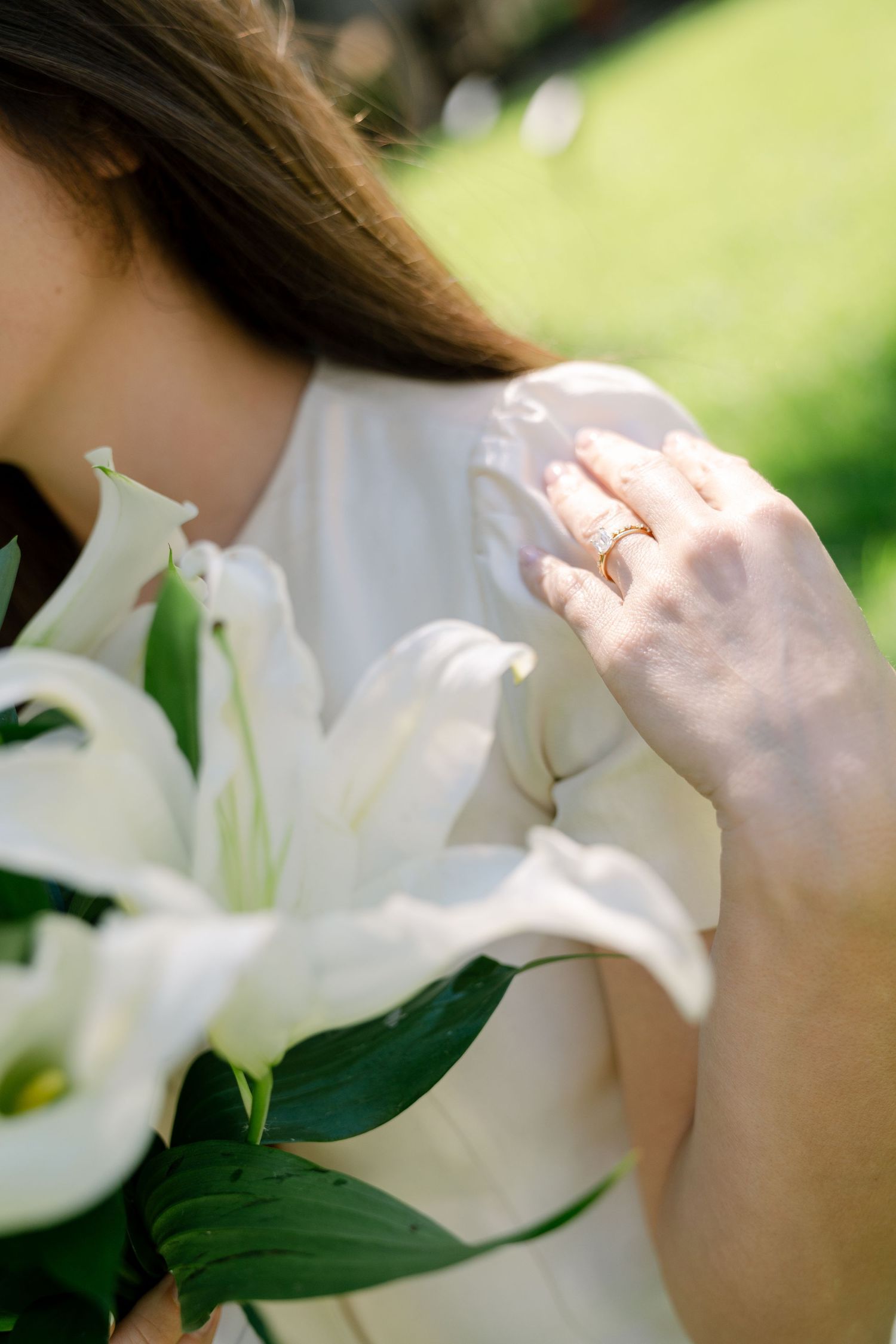 White lily flowers bloom in soft natural light against a blurred green garden background.