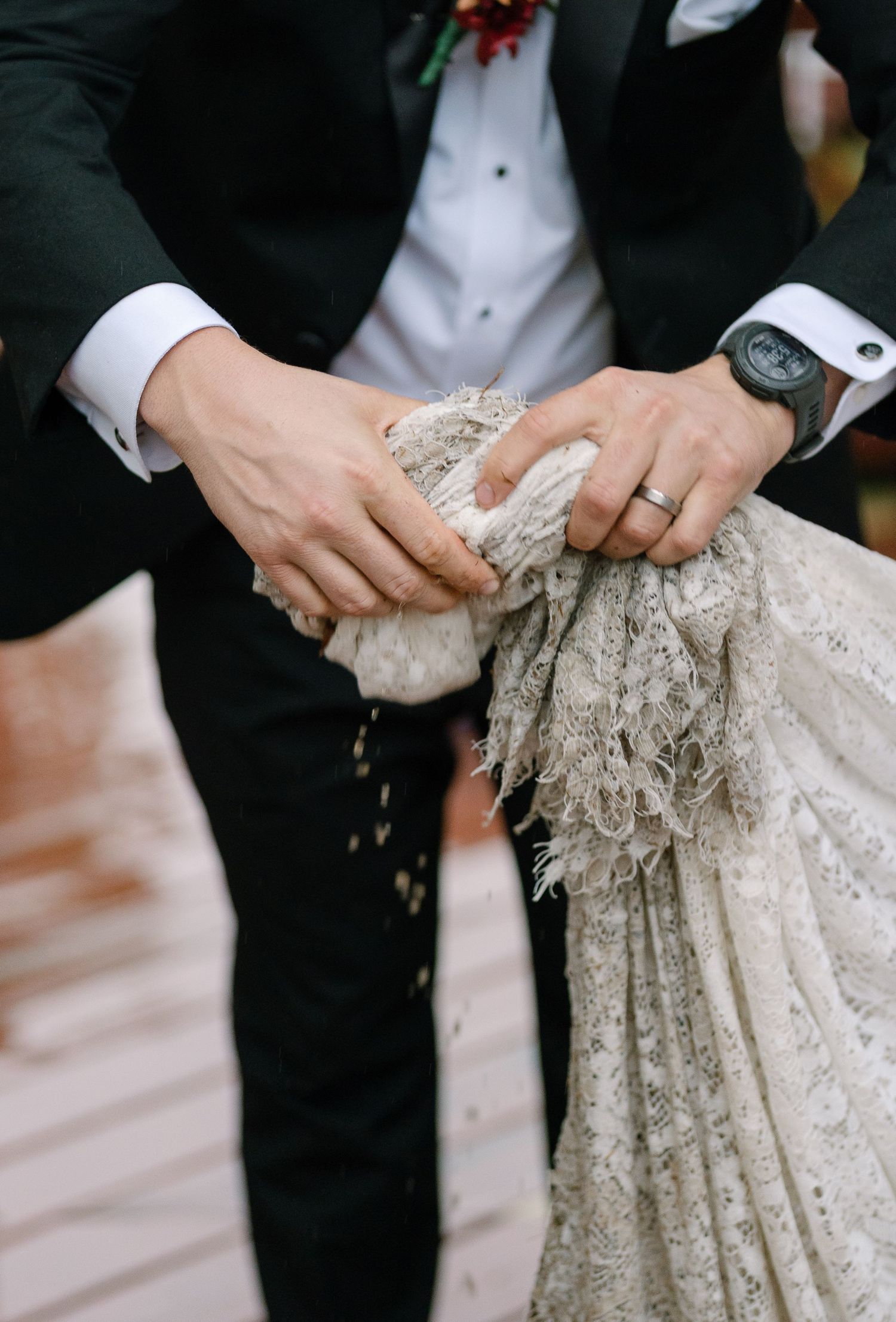 Close-up view of hands holding delicate lace details on an ornate dress.