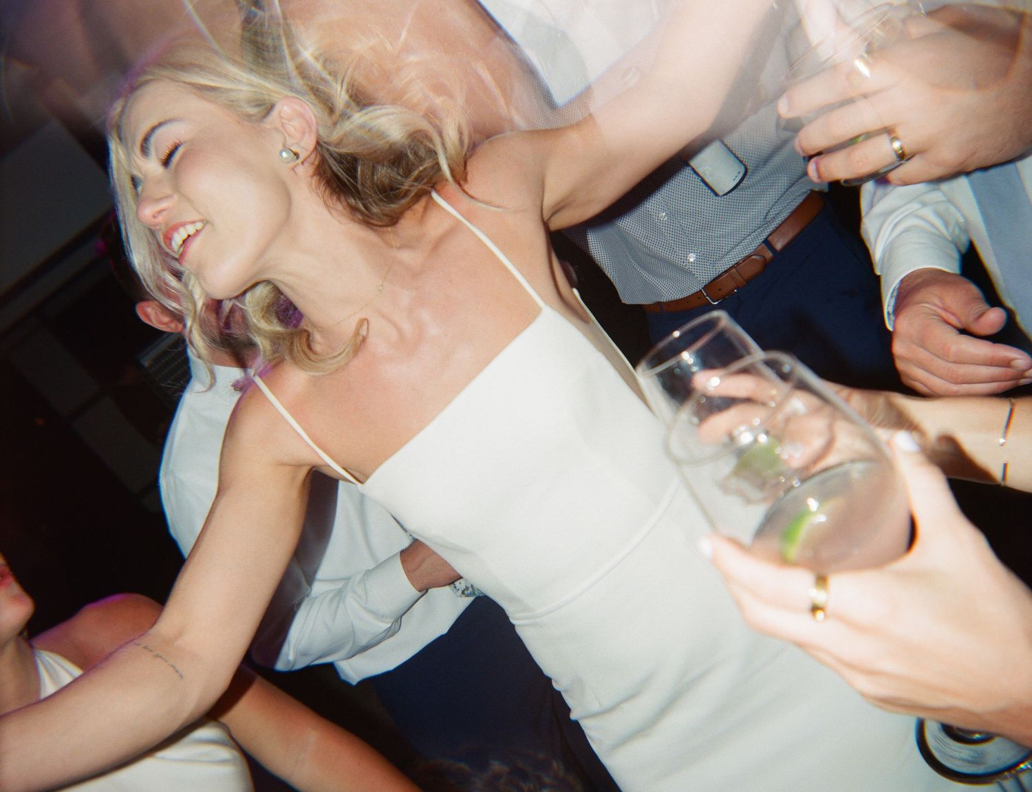 Wedding celebration candid shows dancing and revelry with guests holding champagne glasses.