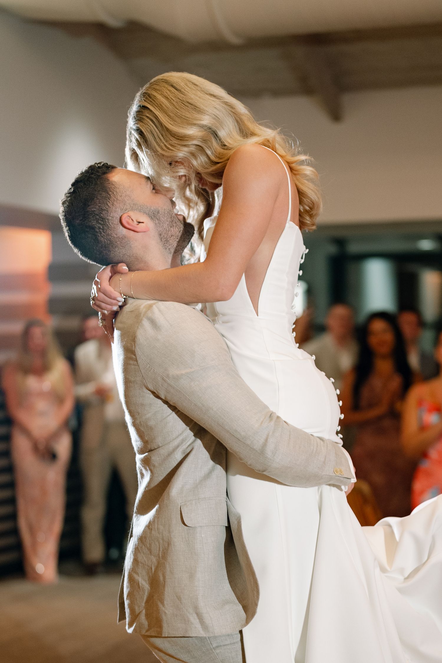 Wedding couple sharing their first dance surrounded by guests at reception.