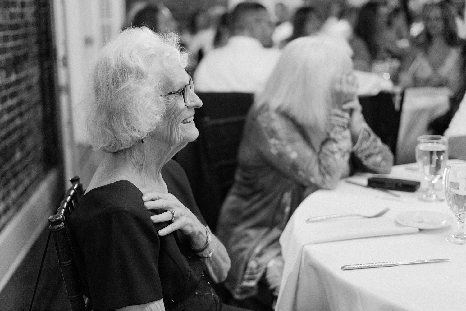 Black and white photo of people sitting at tables in a restaurant, with one person laughing joyfully.