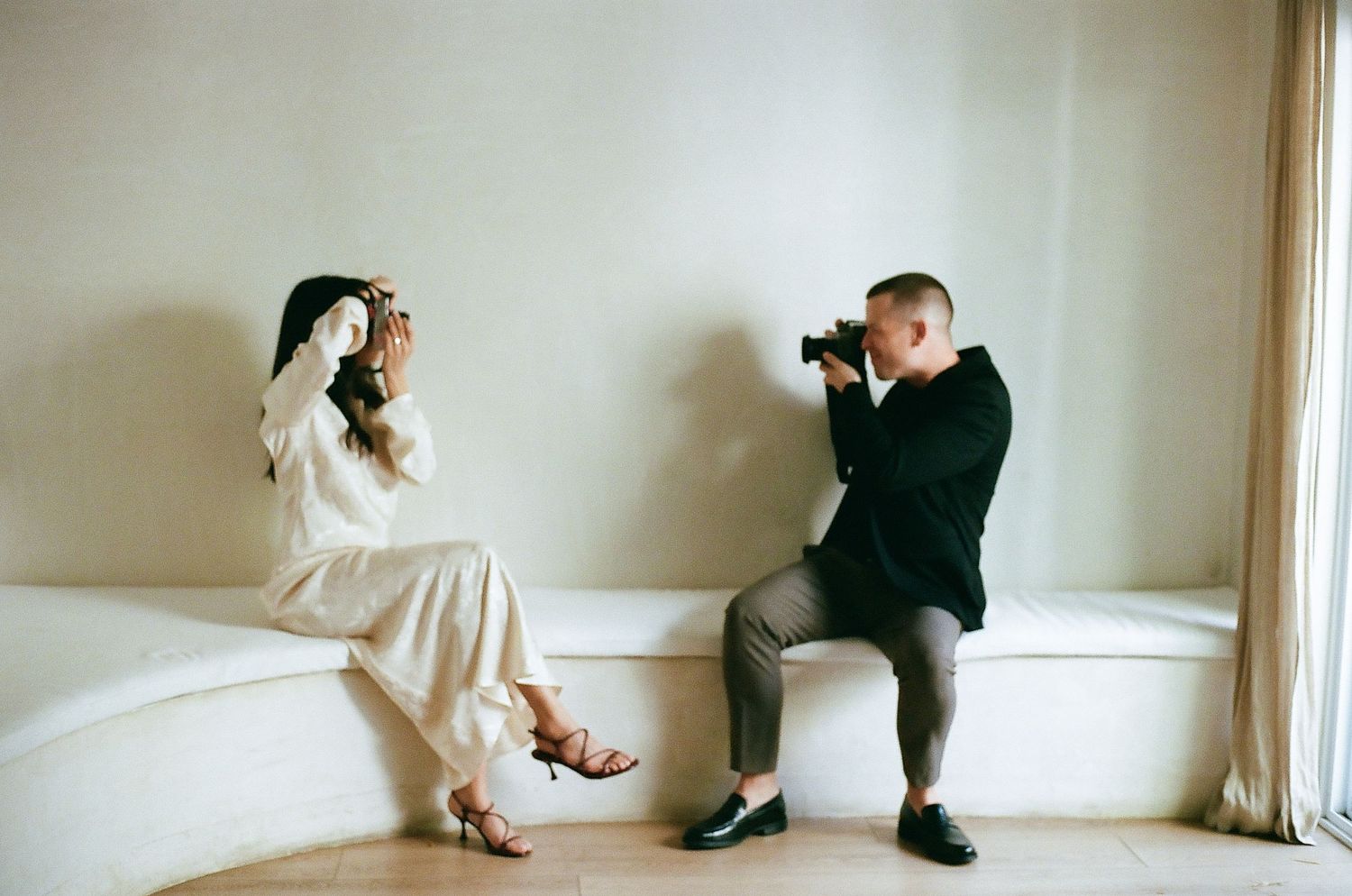 Panoramic sequence showing two people interacting along a minimalist white wall.