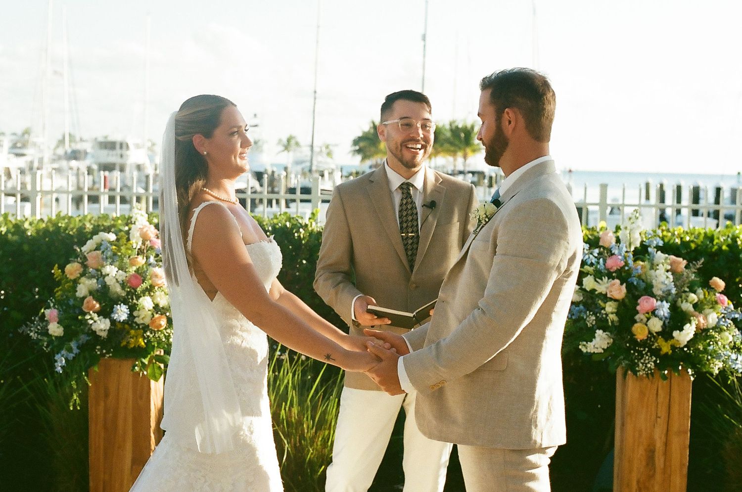 Wedding ceremony takes place in a modern venue with wooden accents and pink floral decorations.