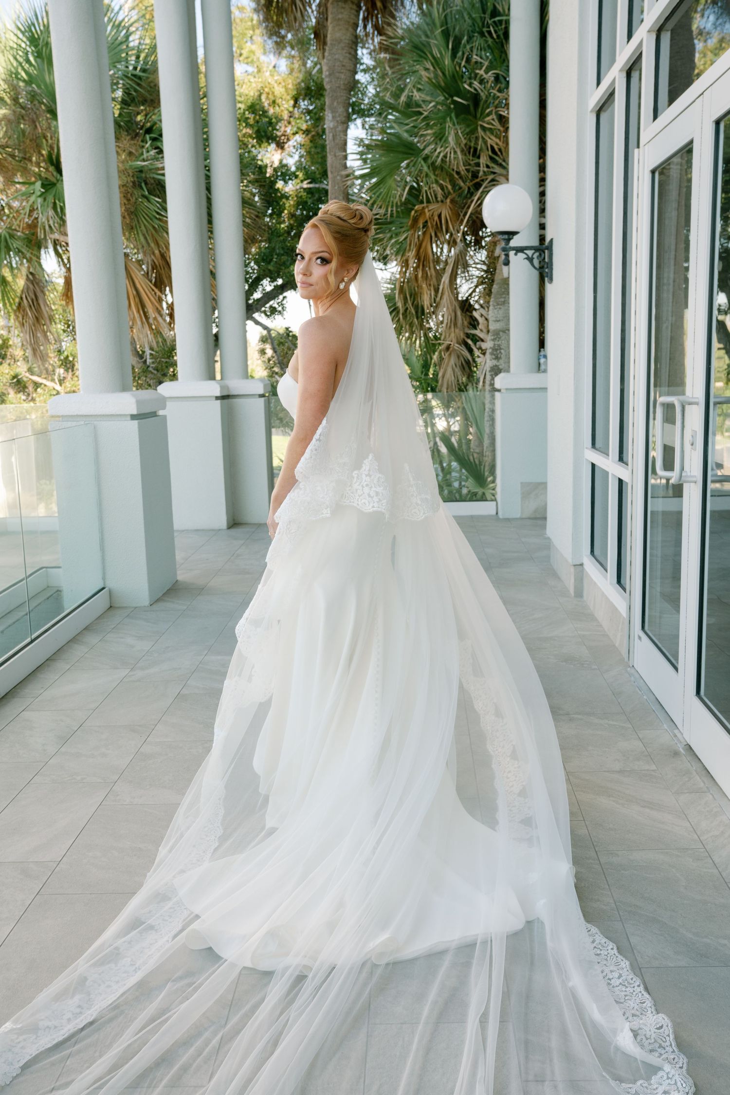 Elegant bridal portraits along a white columned porch with palm trees in the background.