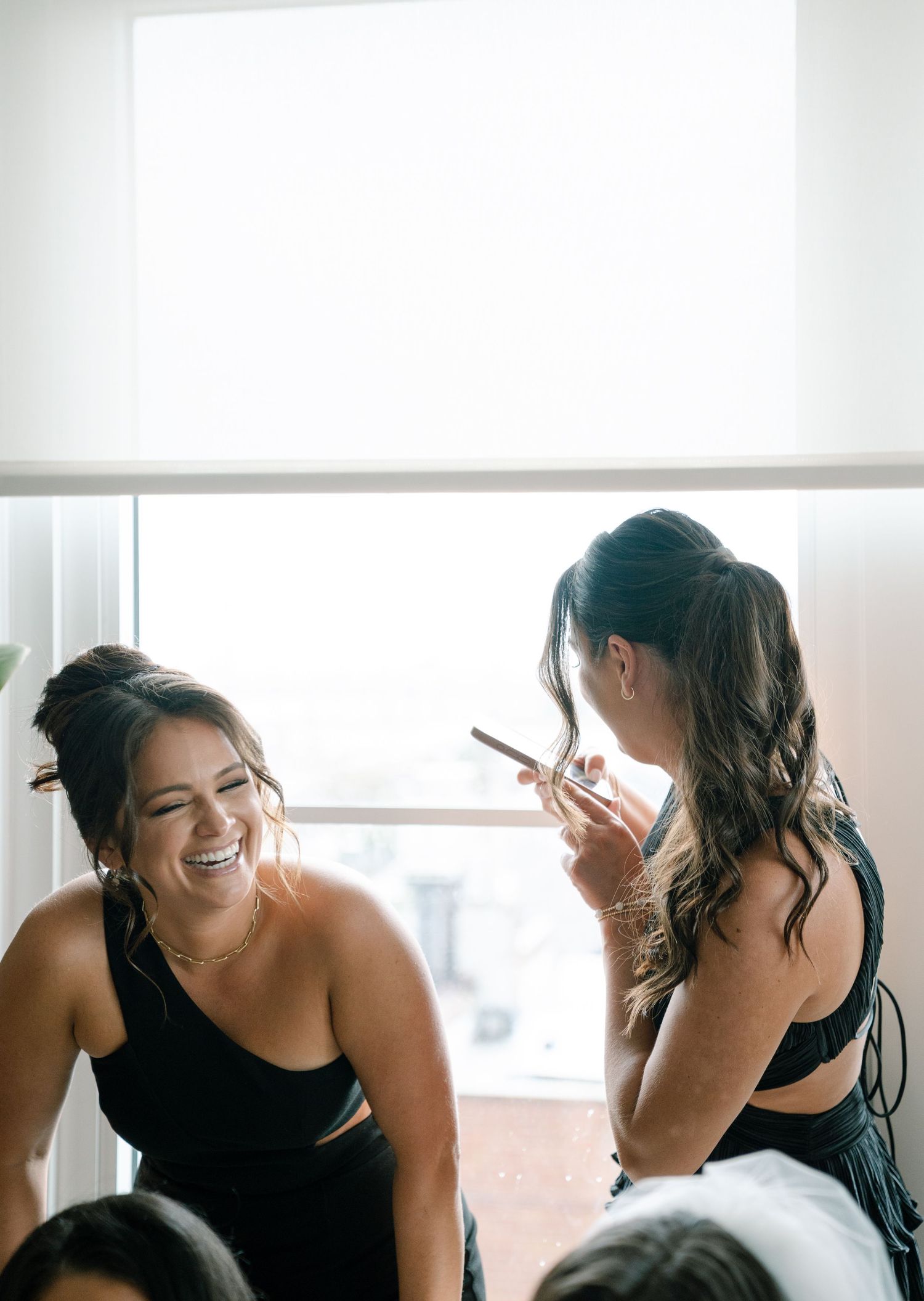 Candid sequence of women in black dresses sharing joyful moments by a window.