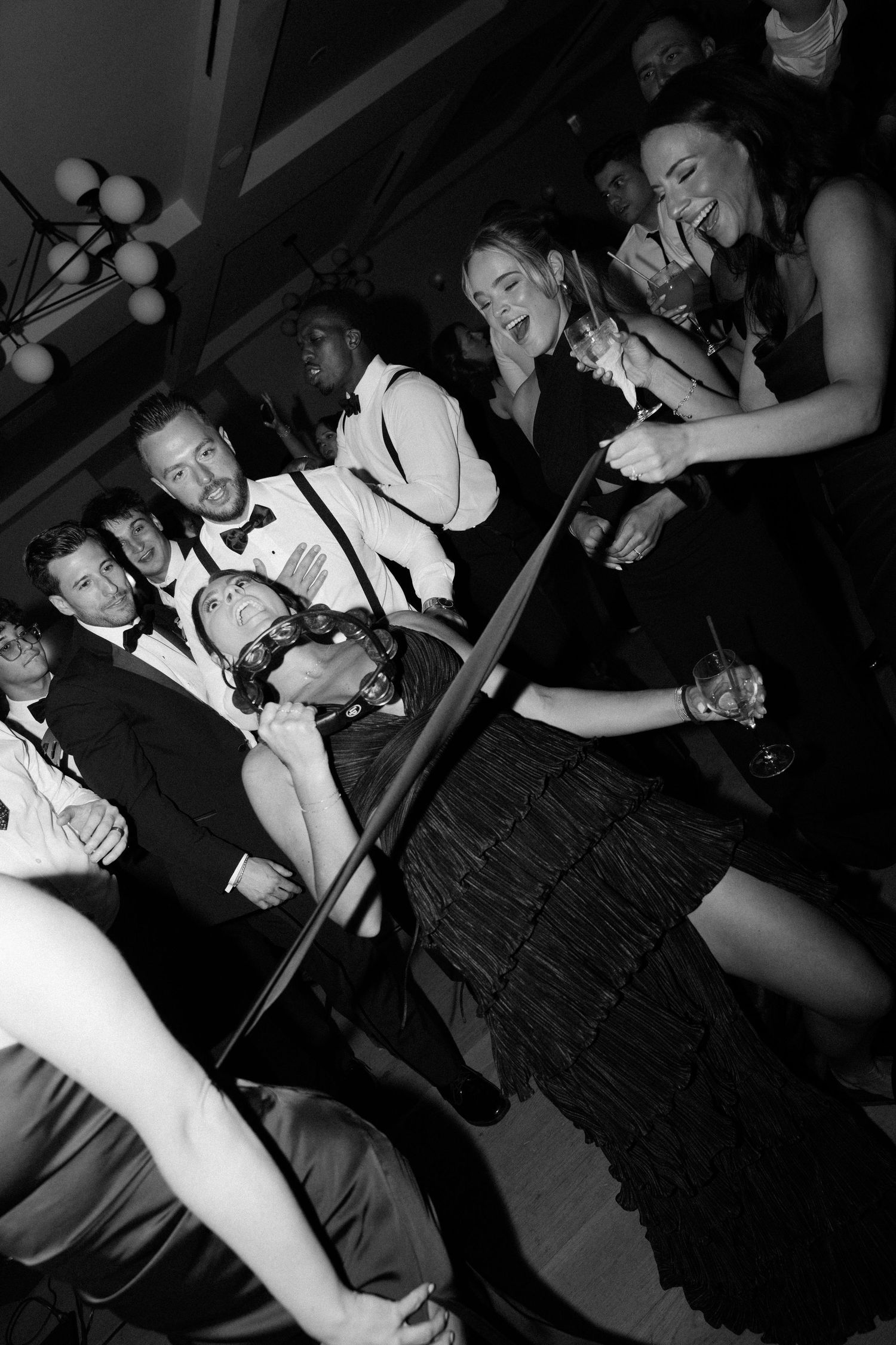 Wedding guests dancing and laughing together on a crowded dance floor at a reception.