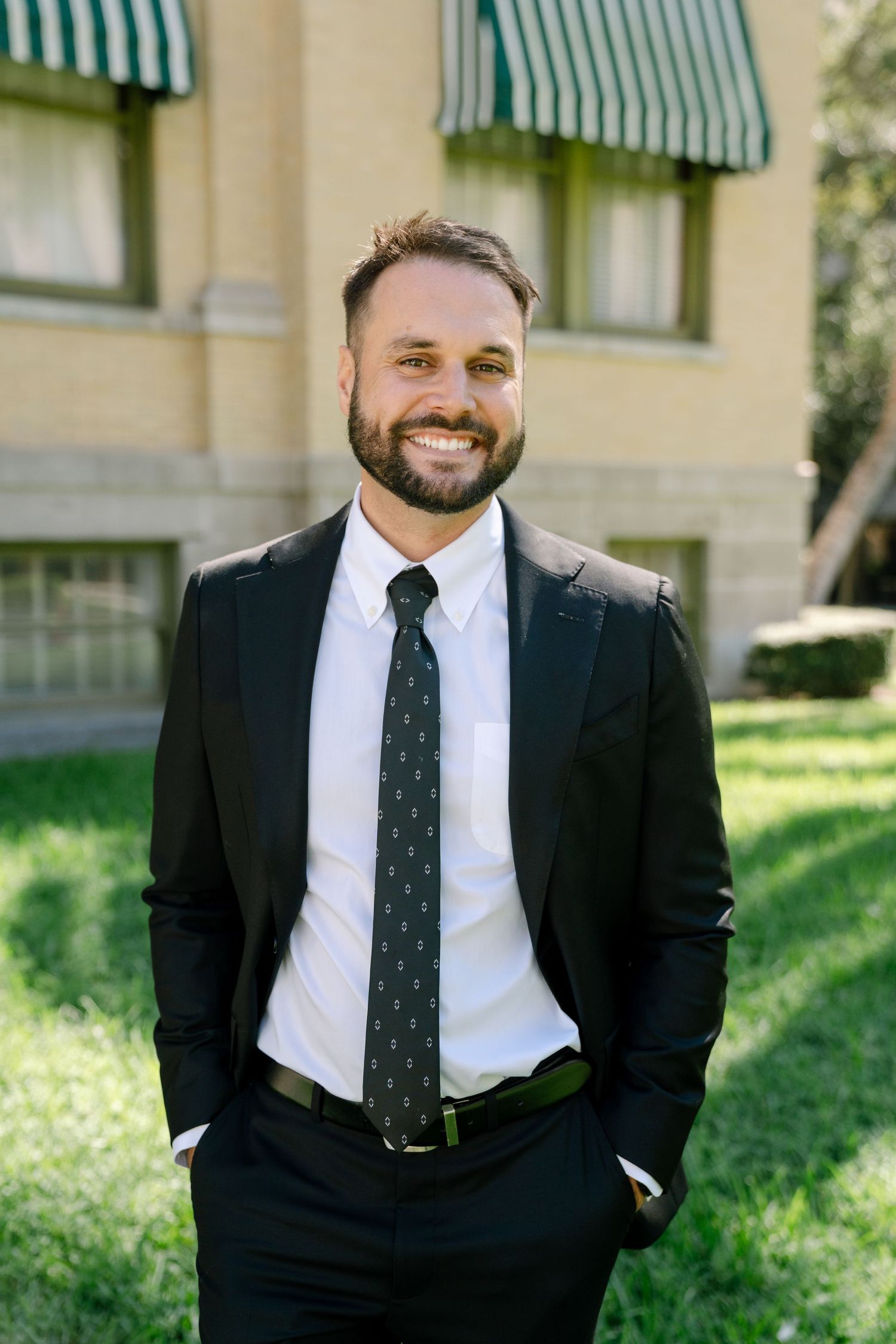 Professional portrait shots showing a person in a black suit and tie against a sunny outdoor backdrop.
