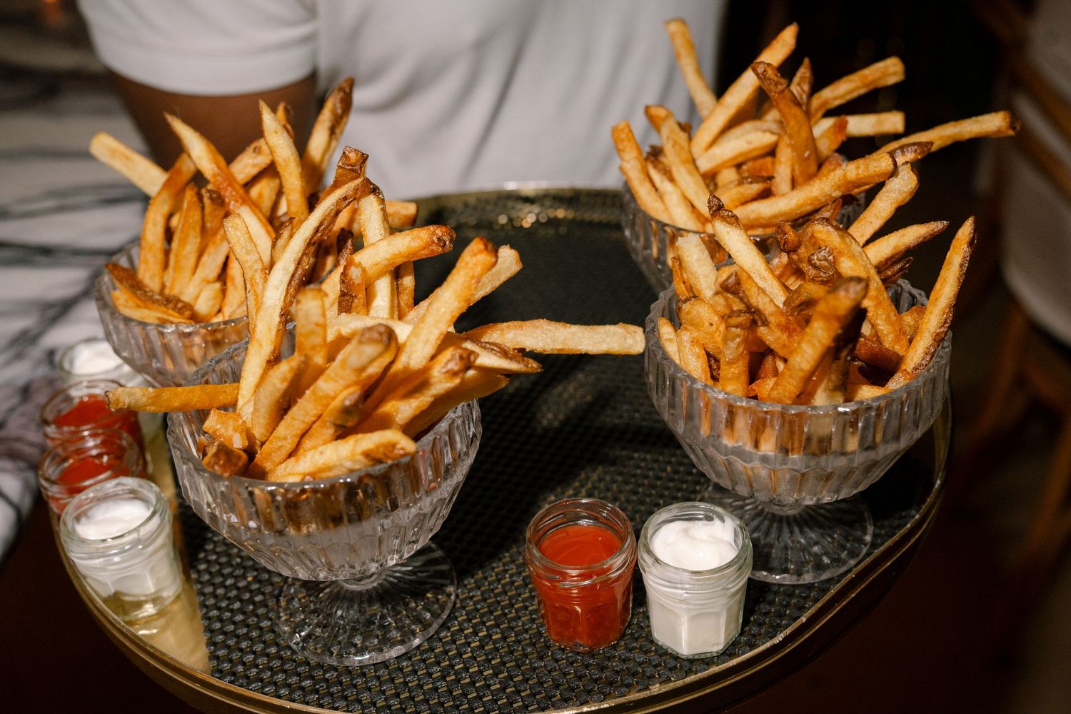 Golden french fries served in crystal bowls with dipping sauce at an elegant event.