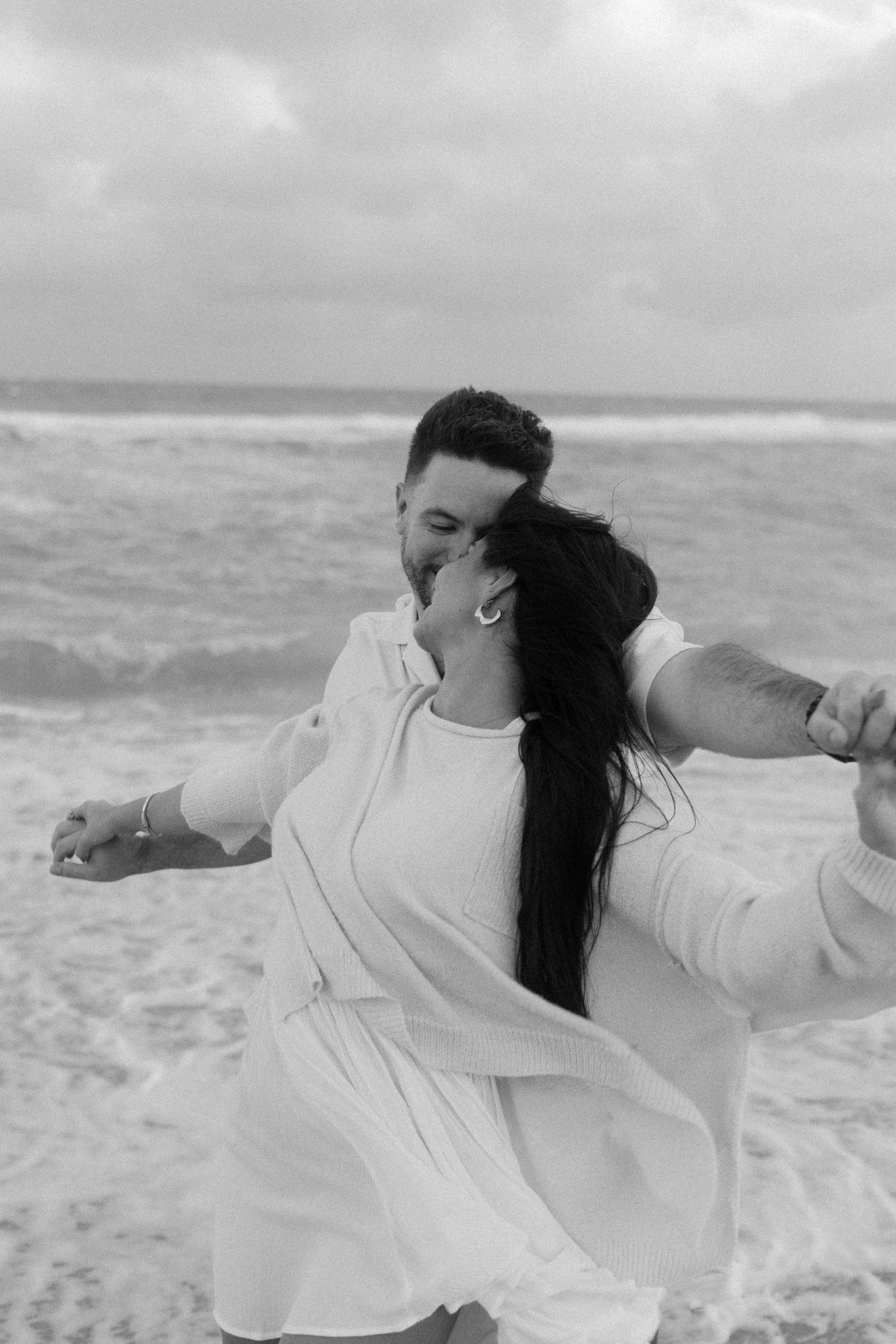 A series of black and white photos showing someone in a white shirt laying on the beach with waves in the background.