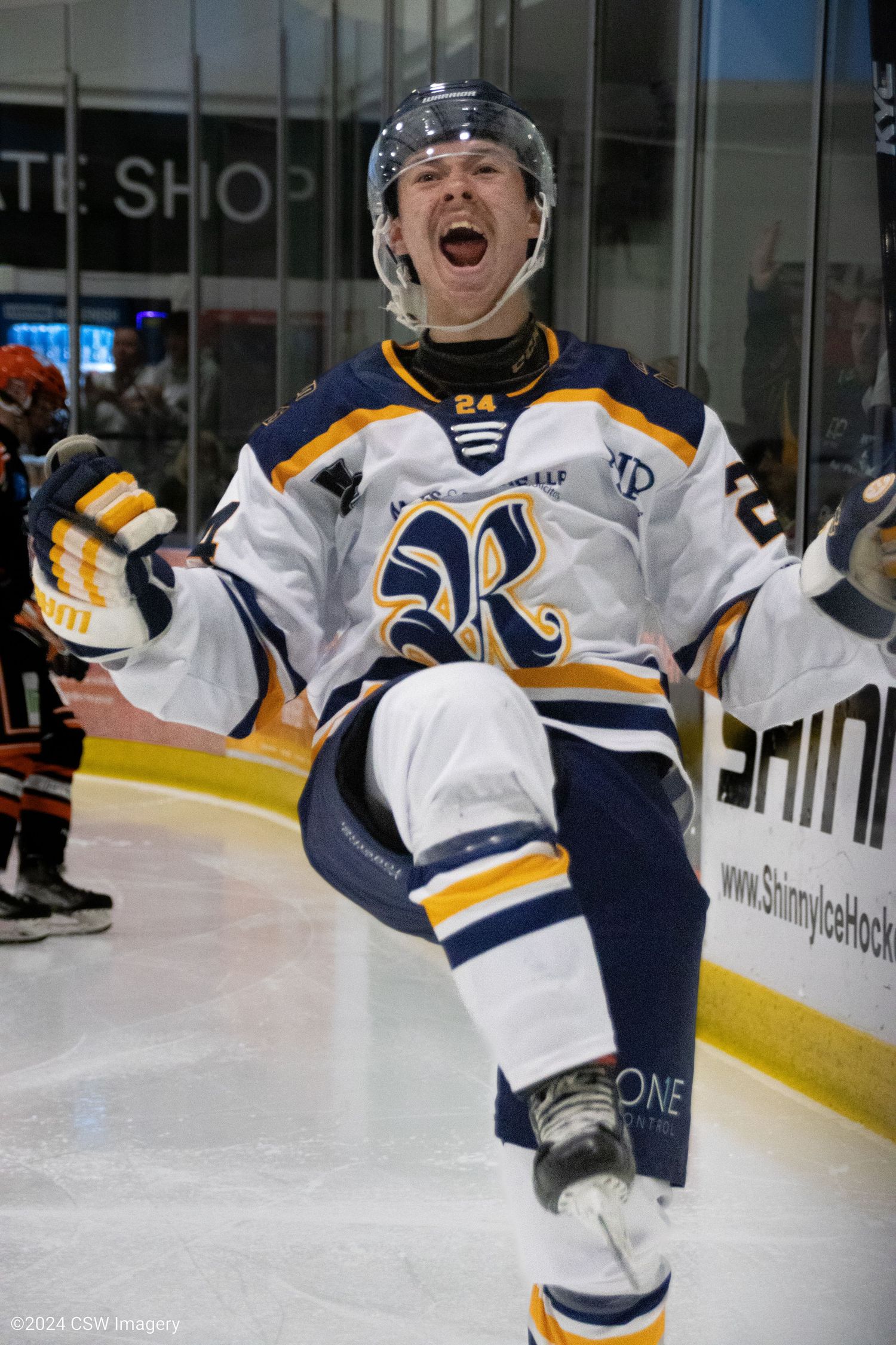 Hockey players in white and navy uniforms celebrating on the ice during a game.