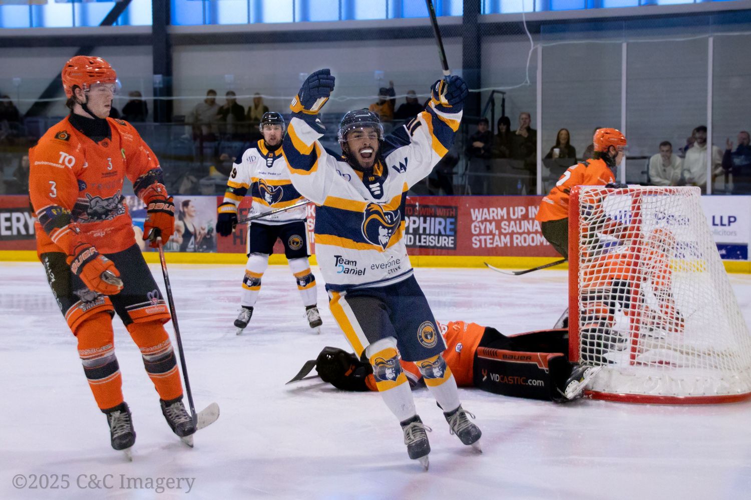 Hockey players chase the puck during a fast-paced game on the ice rink.