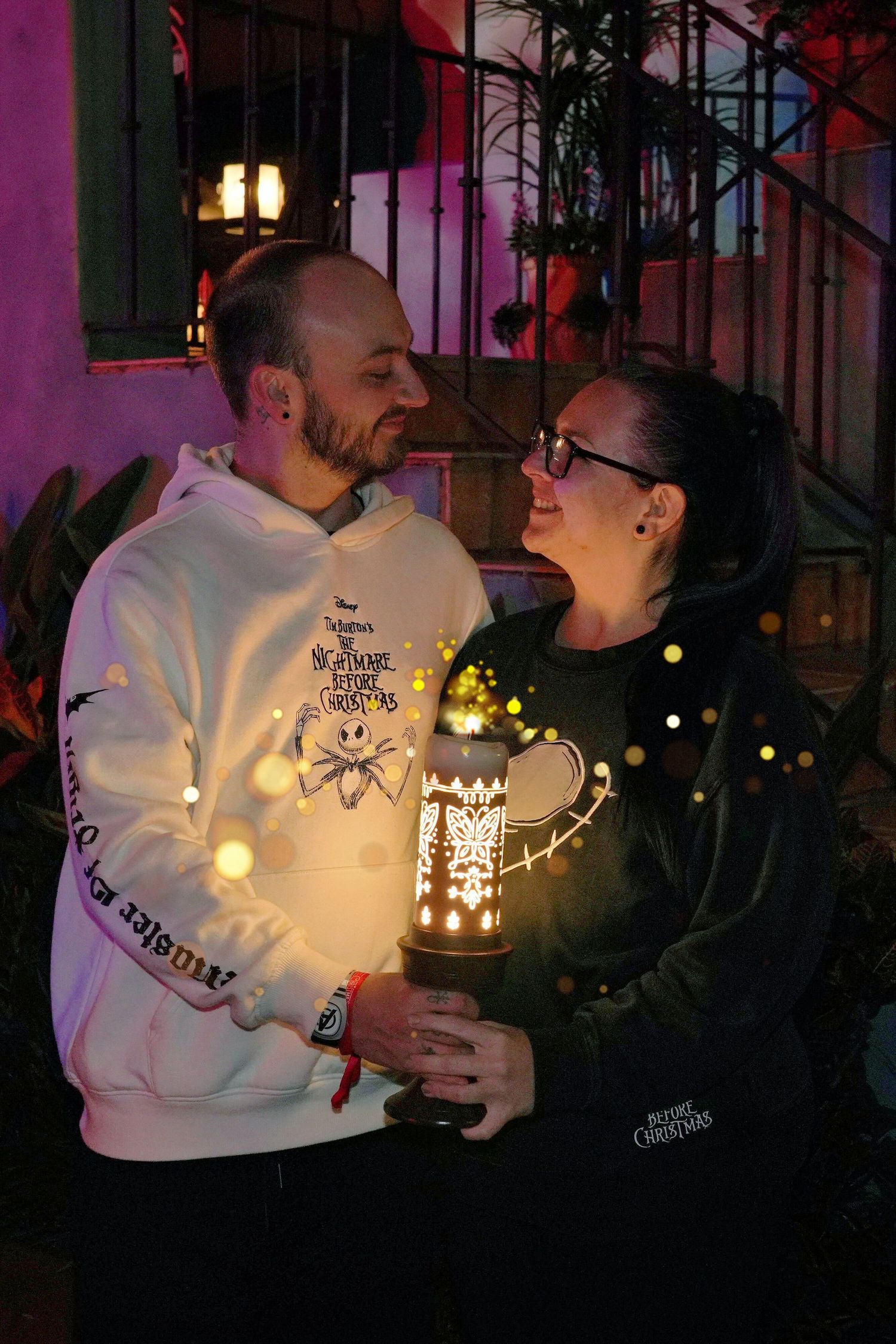 Couple sharing romantic moment with fairy lights and lantern decoration at night.